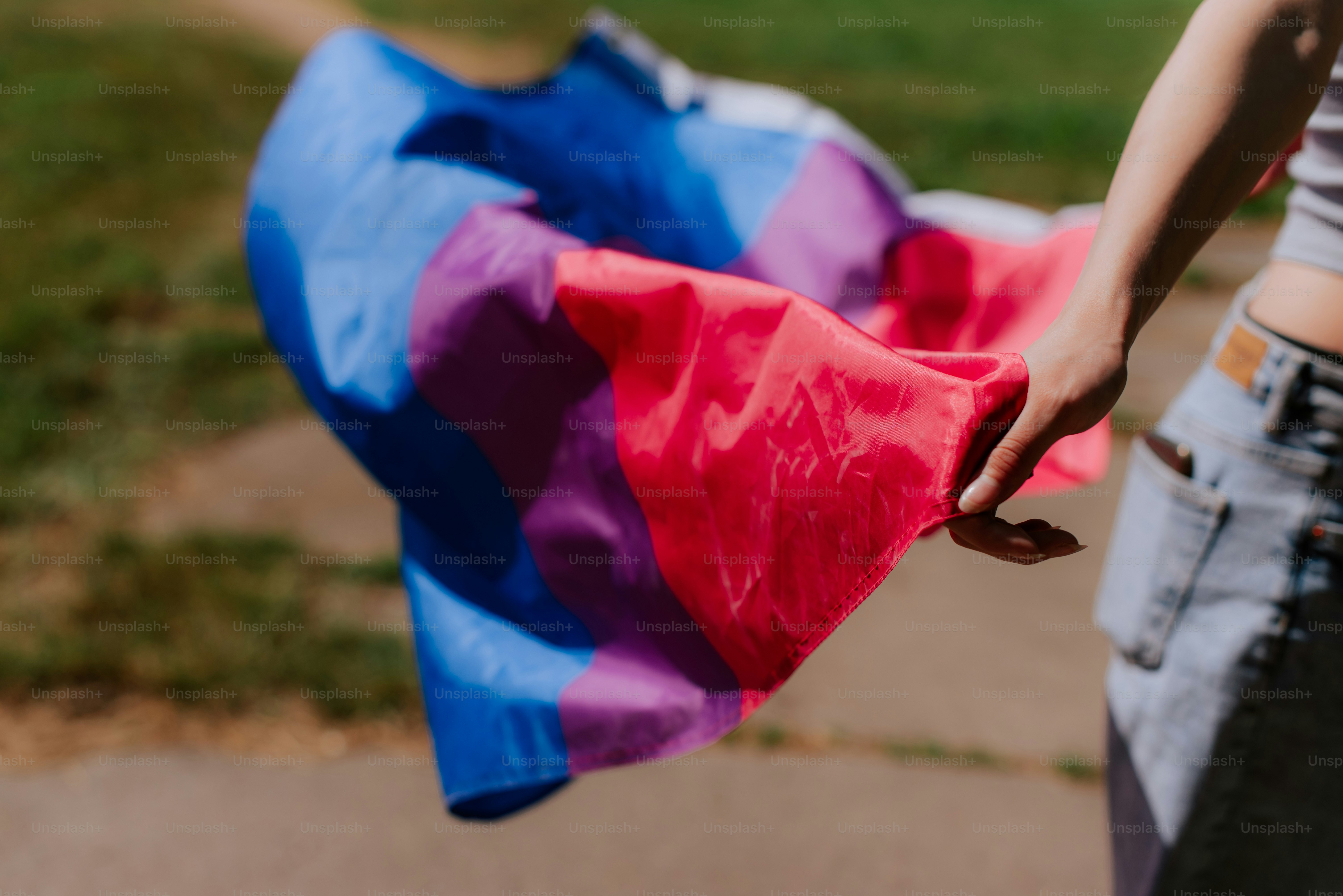 a person holding a blue, pink and purple kite