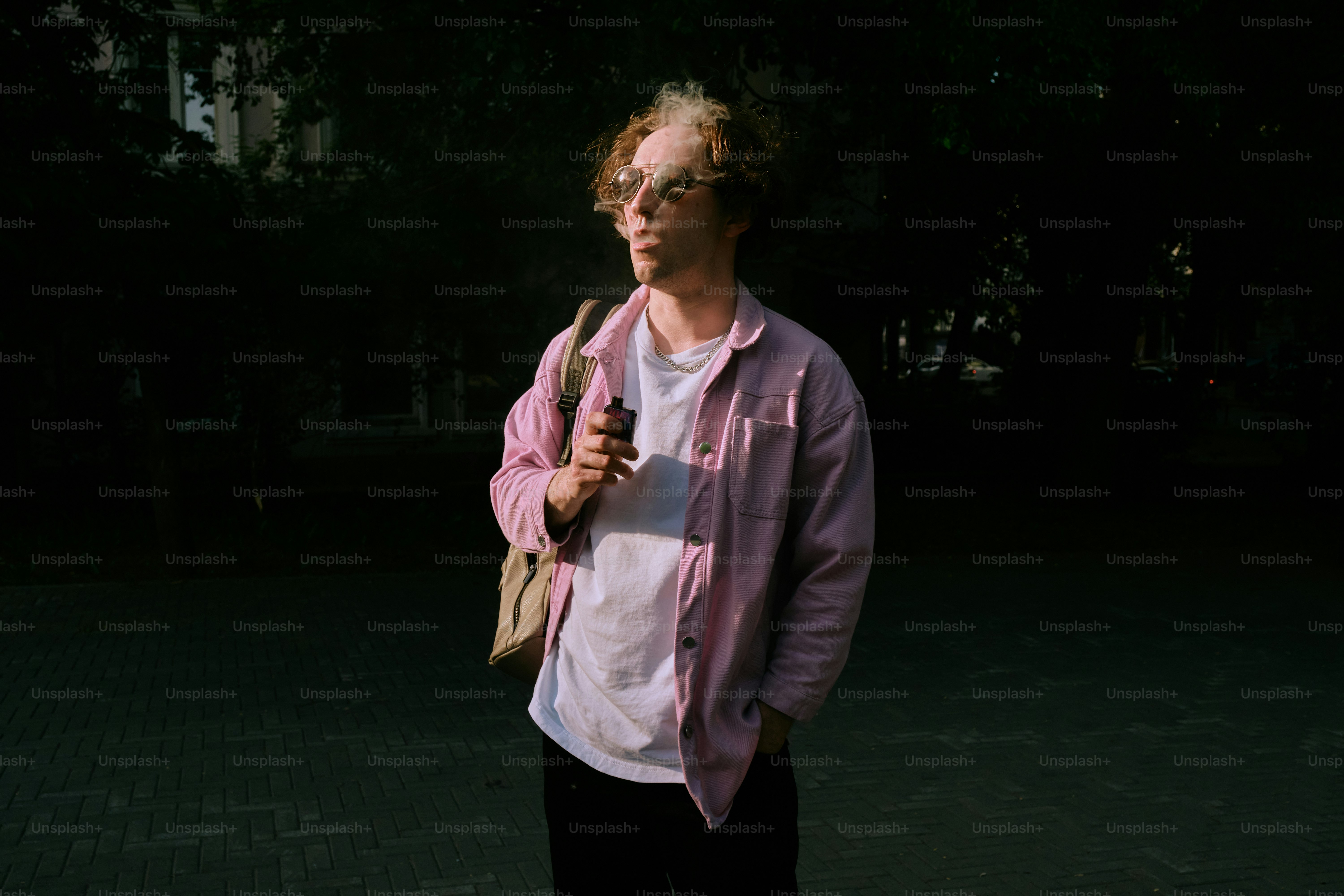 a man in a pink shirt is holding an umbrella