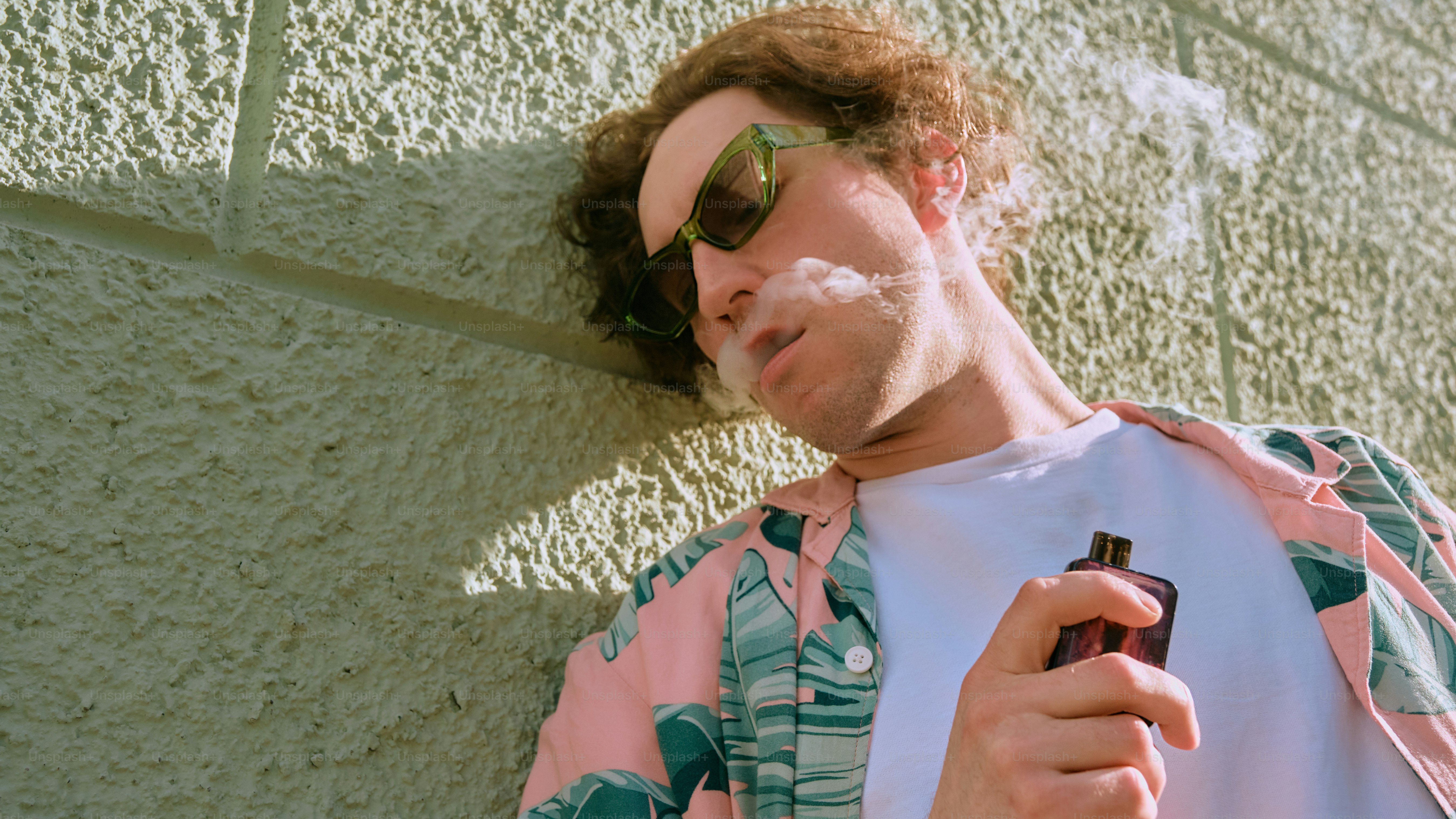 a man smoking a cigarette next to a wall
