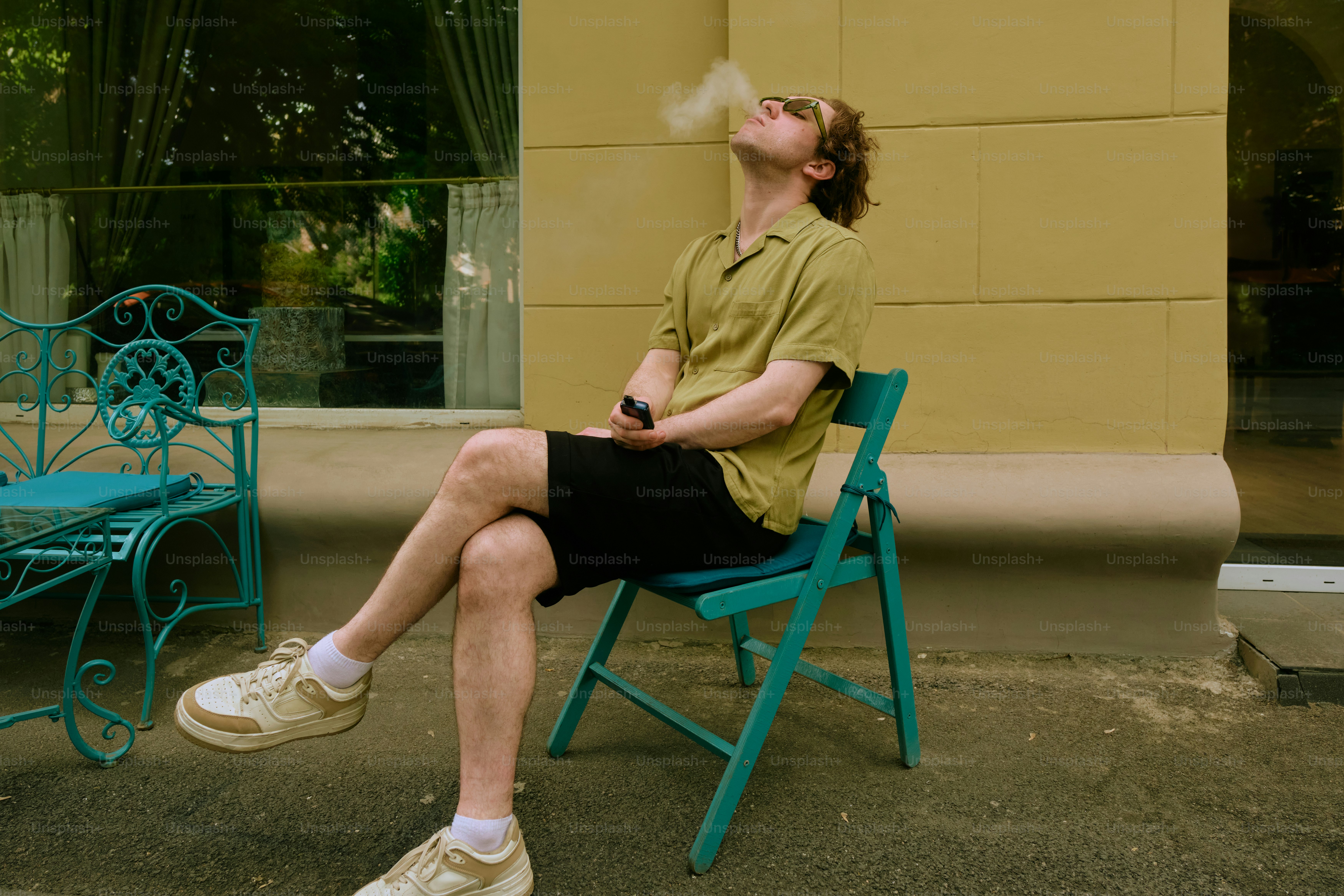 a man sitting on a chair smoking a cigarette