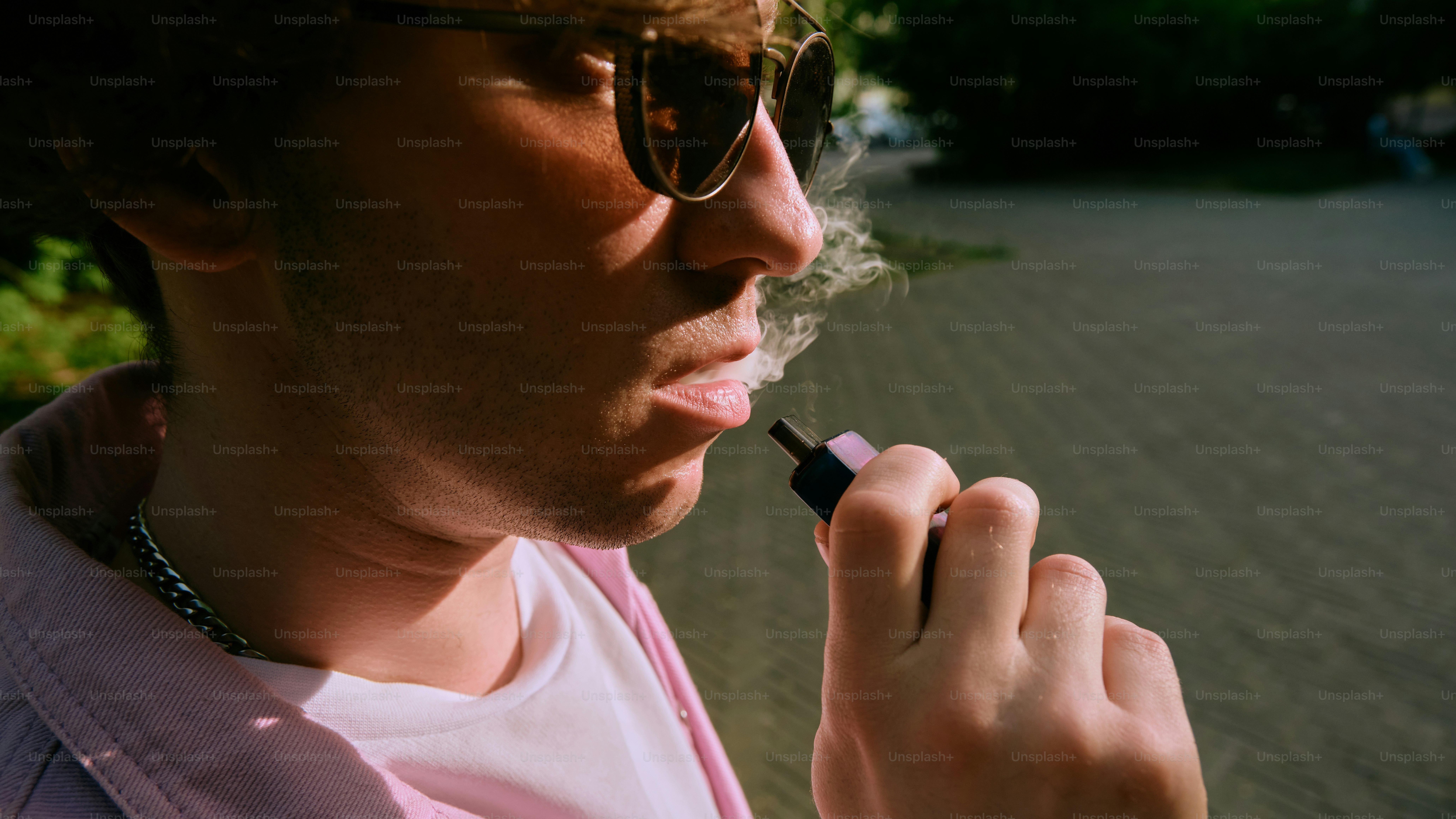 a man smokes a cigarette while wearing sunglasses