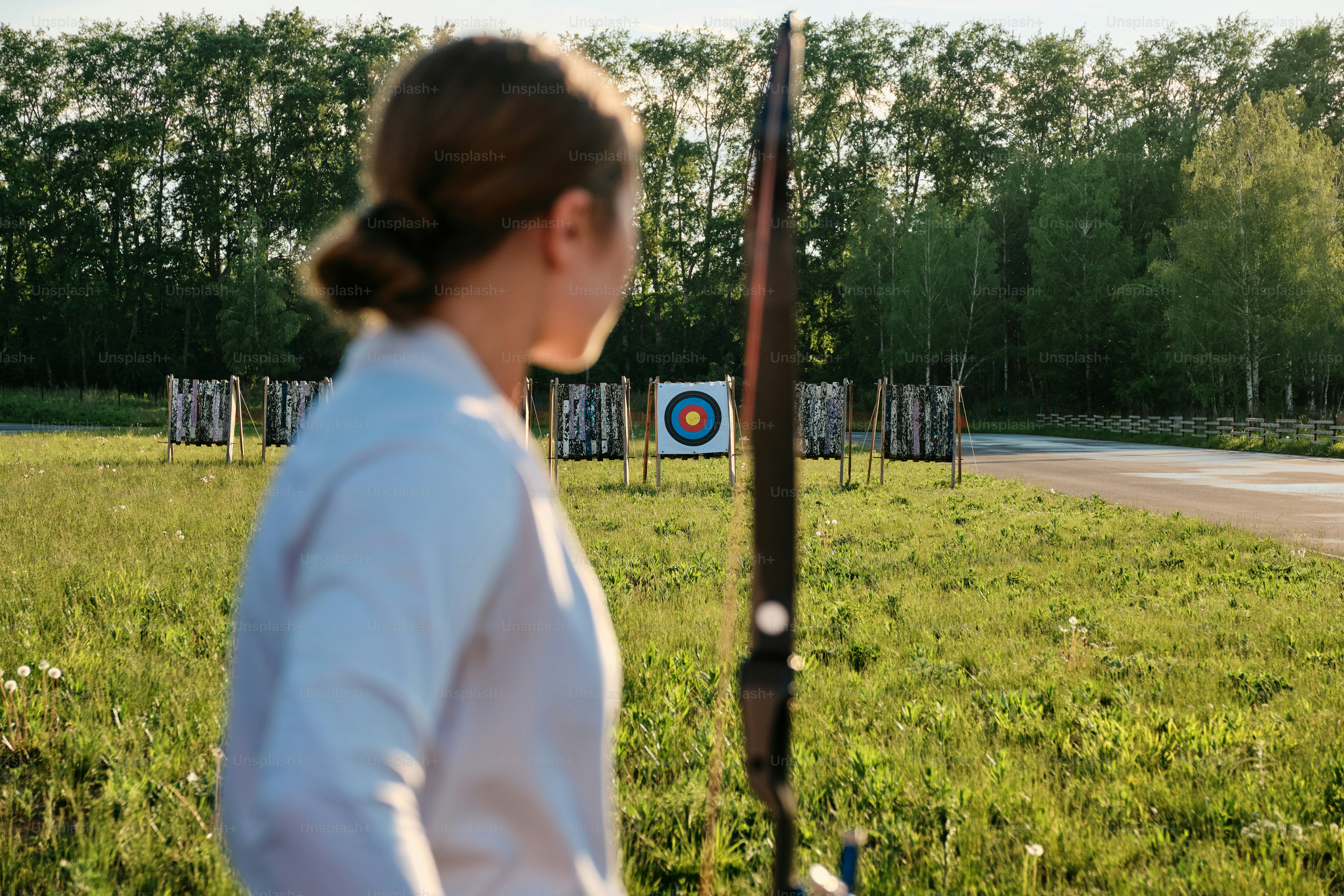 a woman standing in a field with a bow