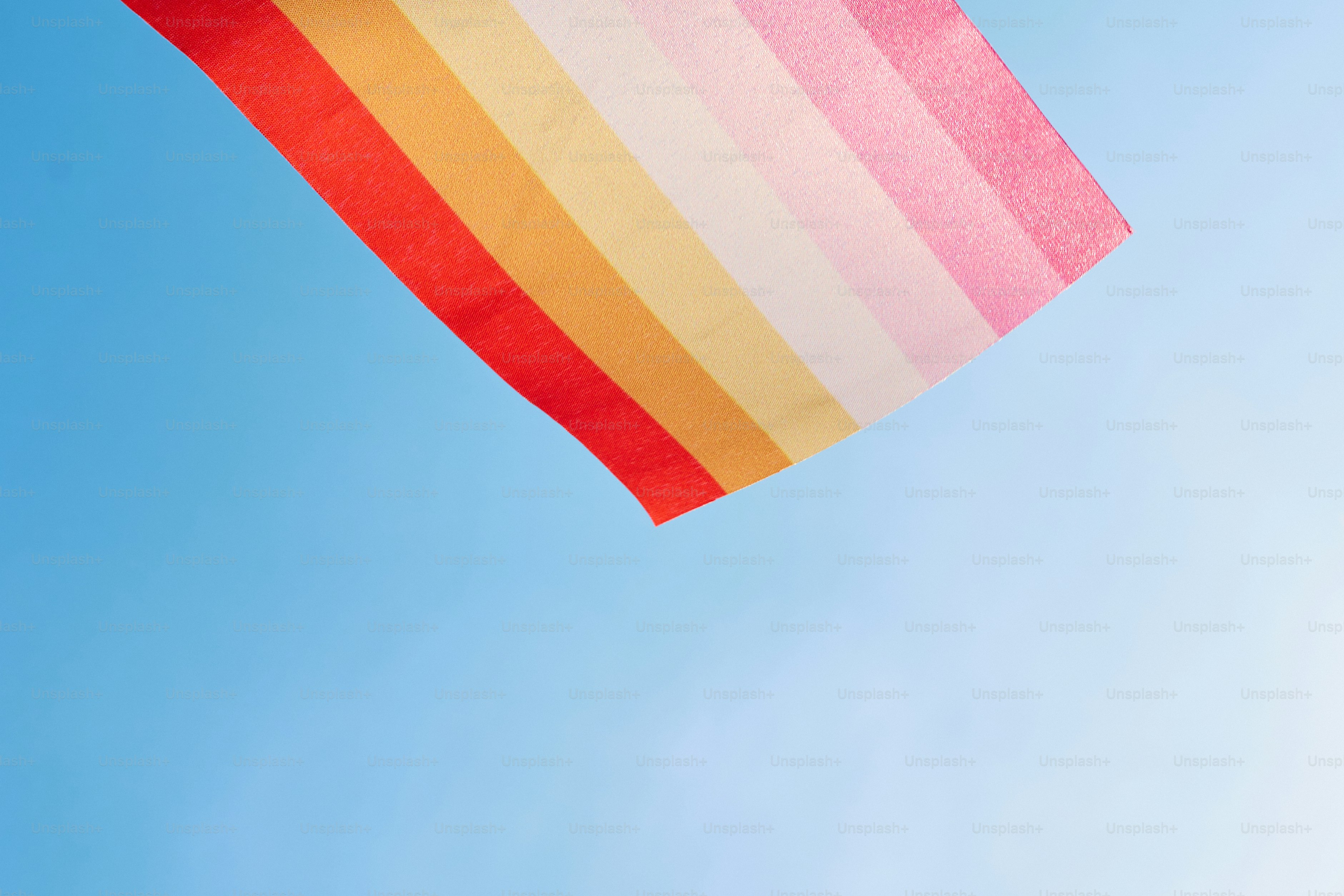 A rainbow colored kite flying in a blue sky