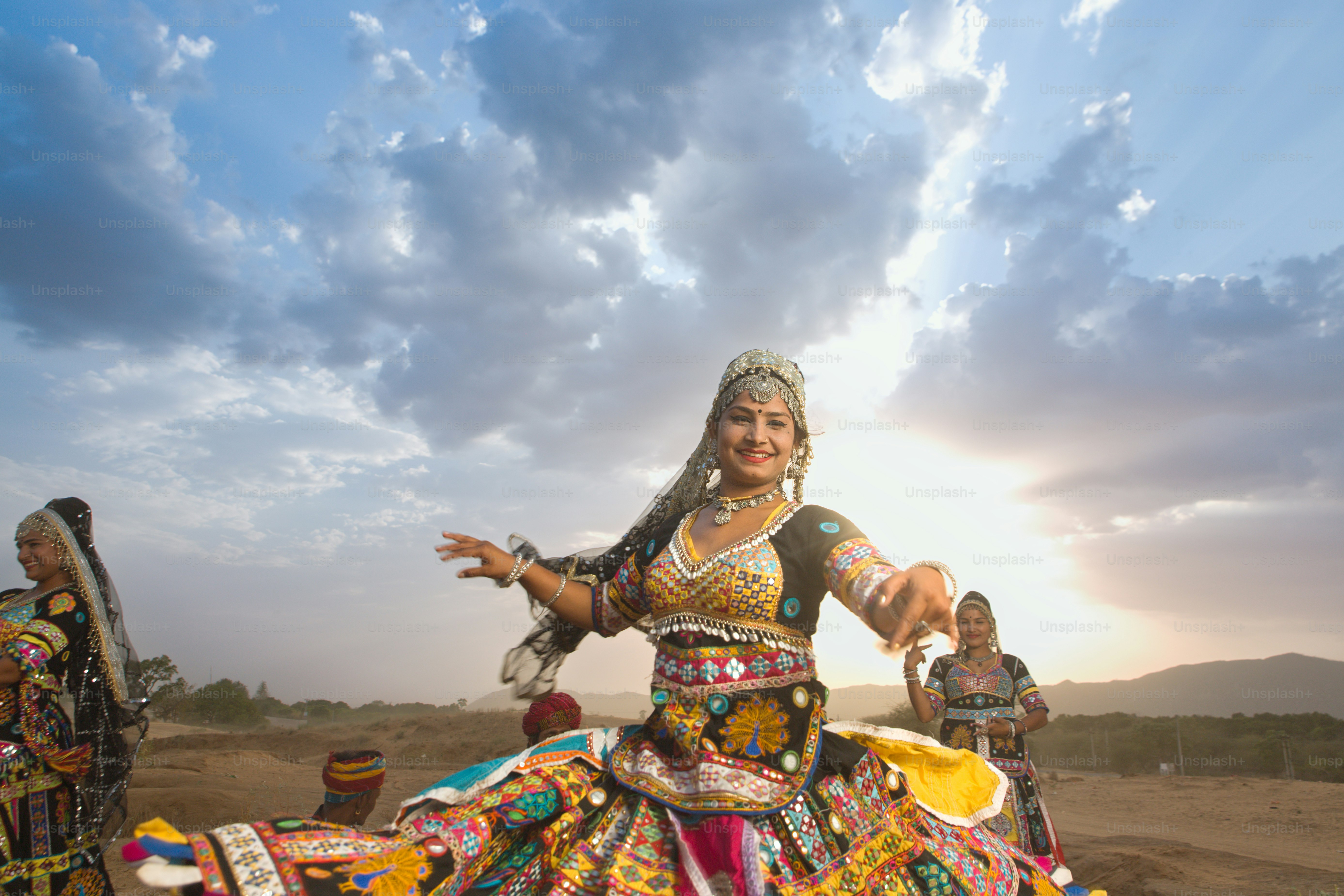 Eine Frau in einem bunten Kleid tanzt in der Wüste