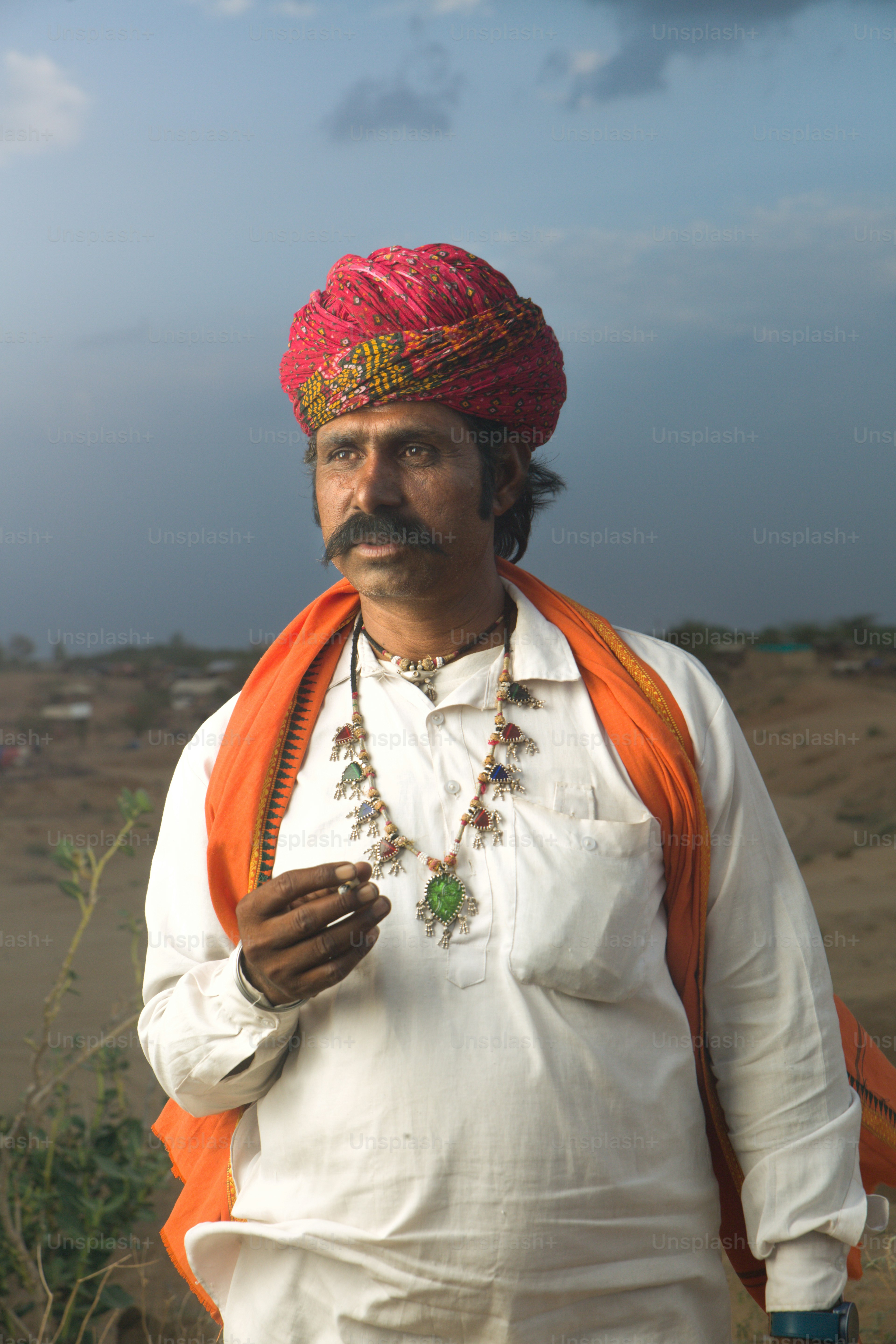 A man in a turban standing in the desert