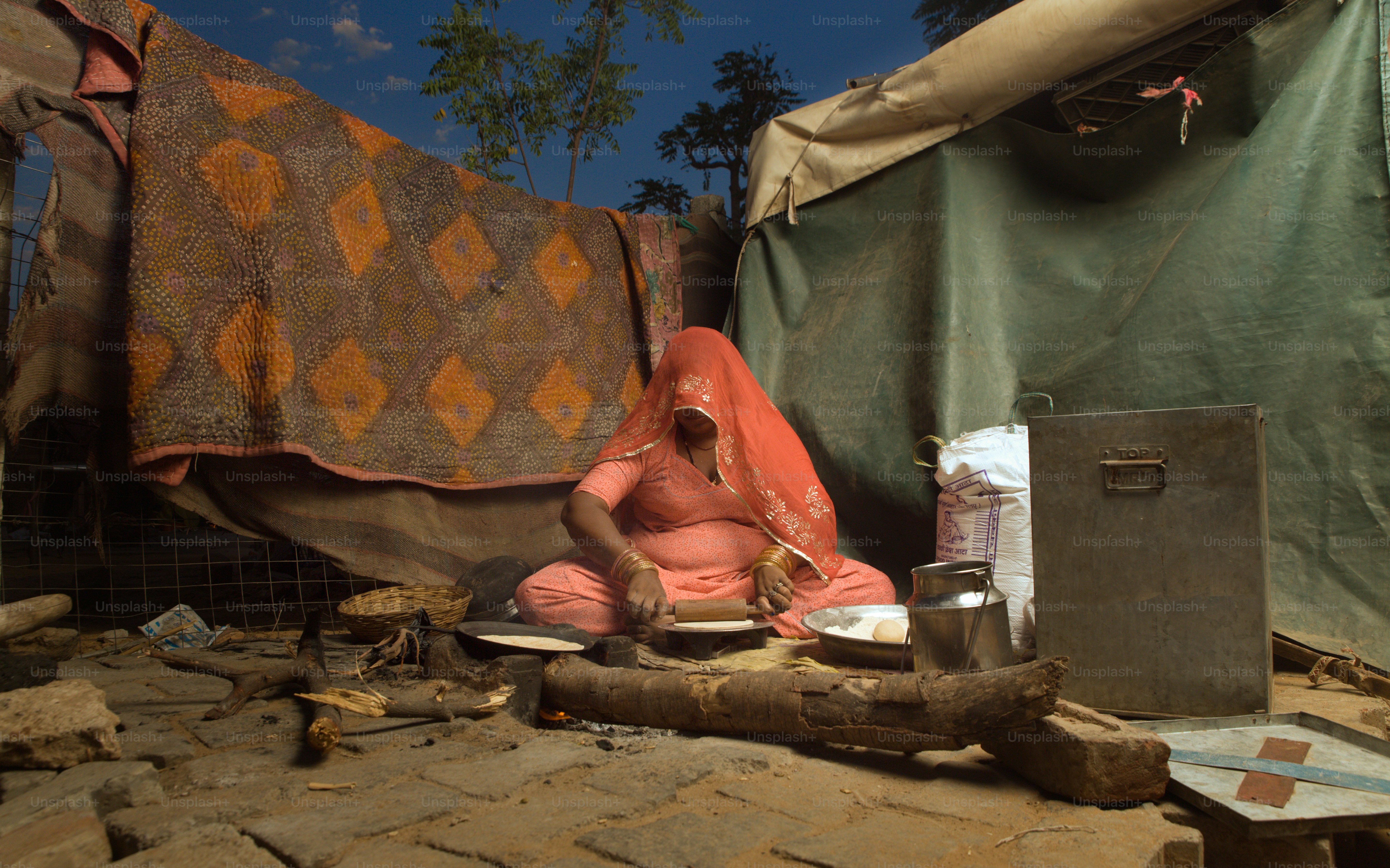 Eine Person, die vor einem Zelt auf dem Boden sitzt