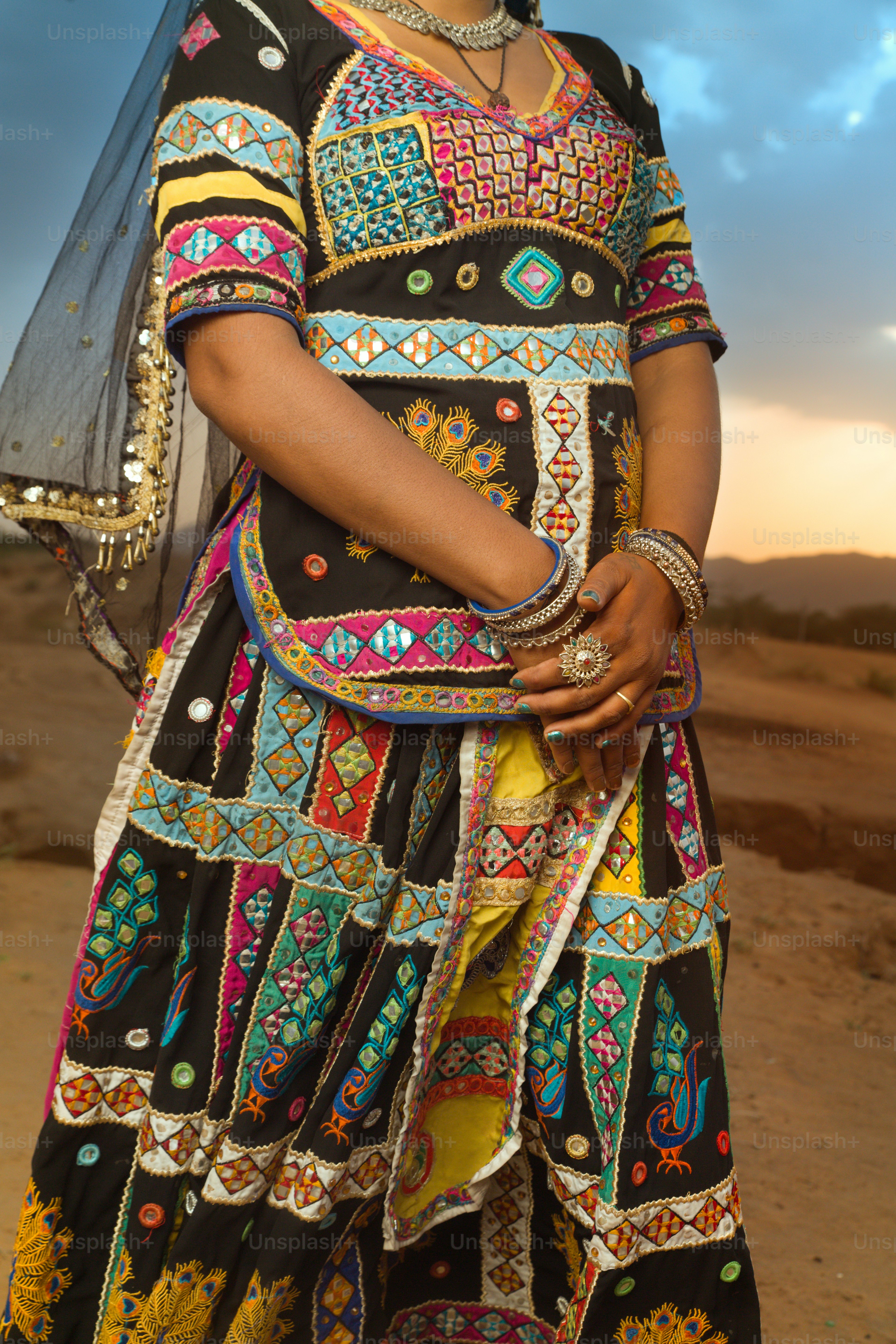 A woman in a colorful dress standing on a dirt road