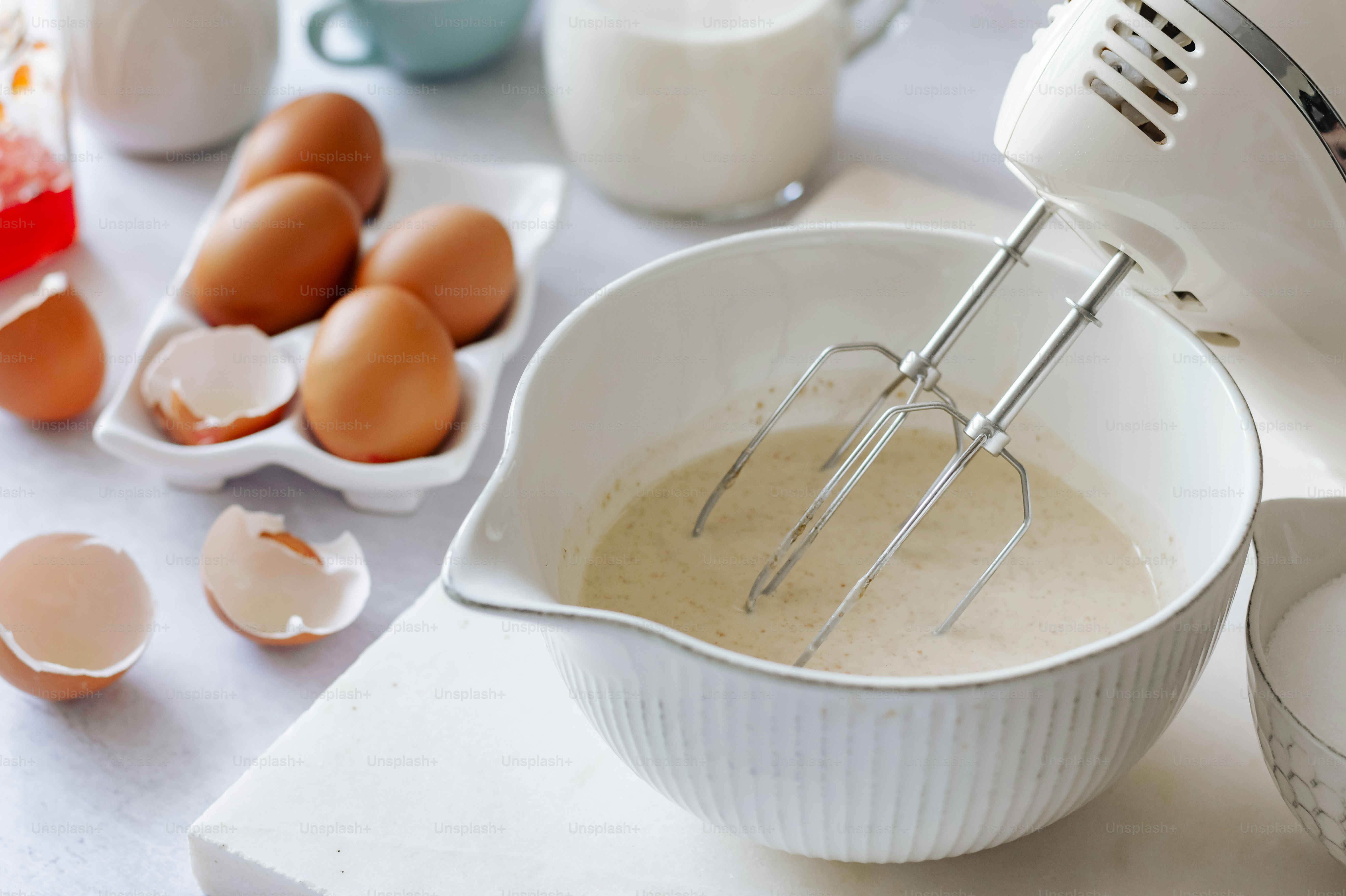 A mixer is mixing eggs in a bowl