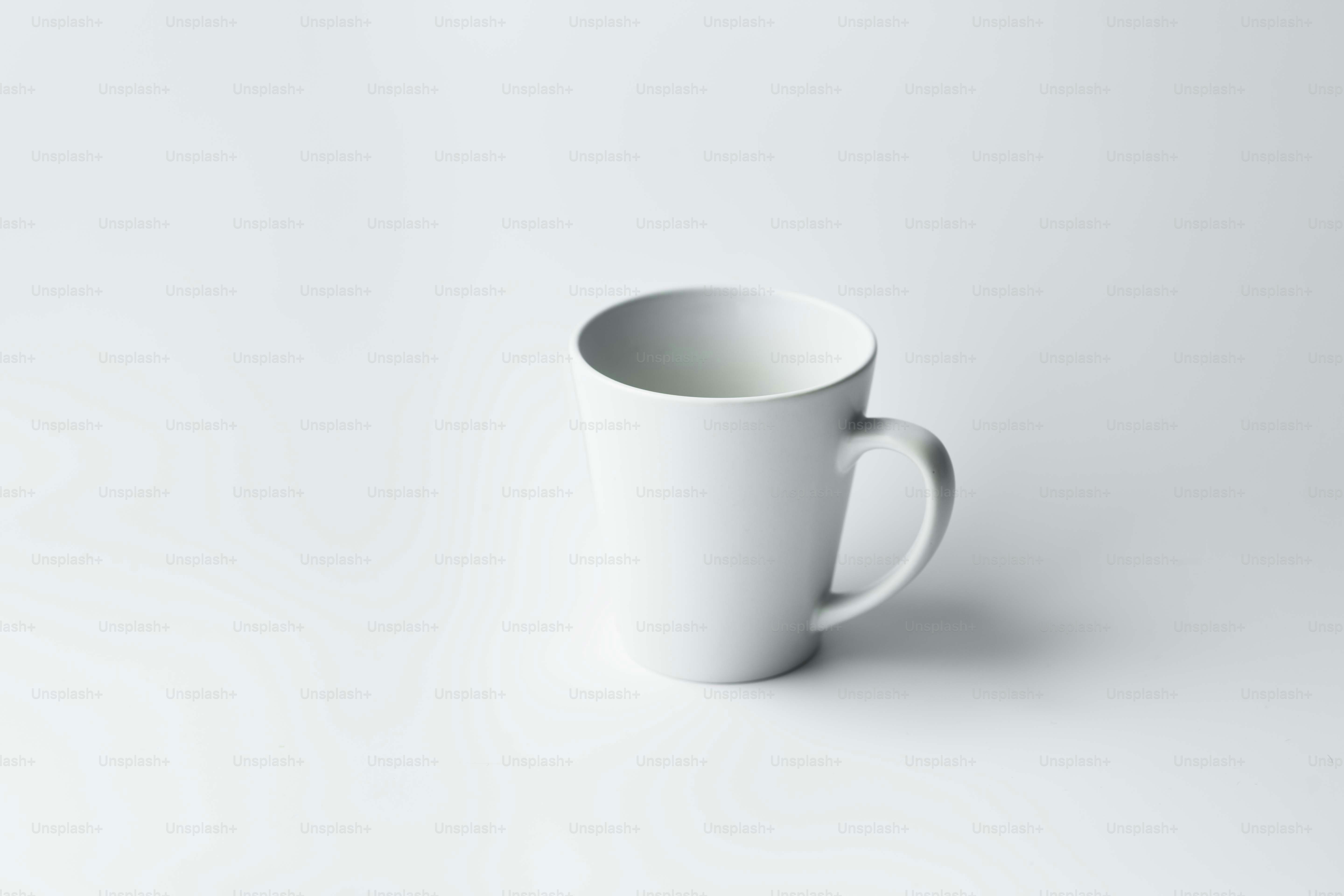 Eine weiße Kaffeetasse auf einem weißen Tisch