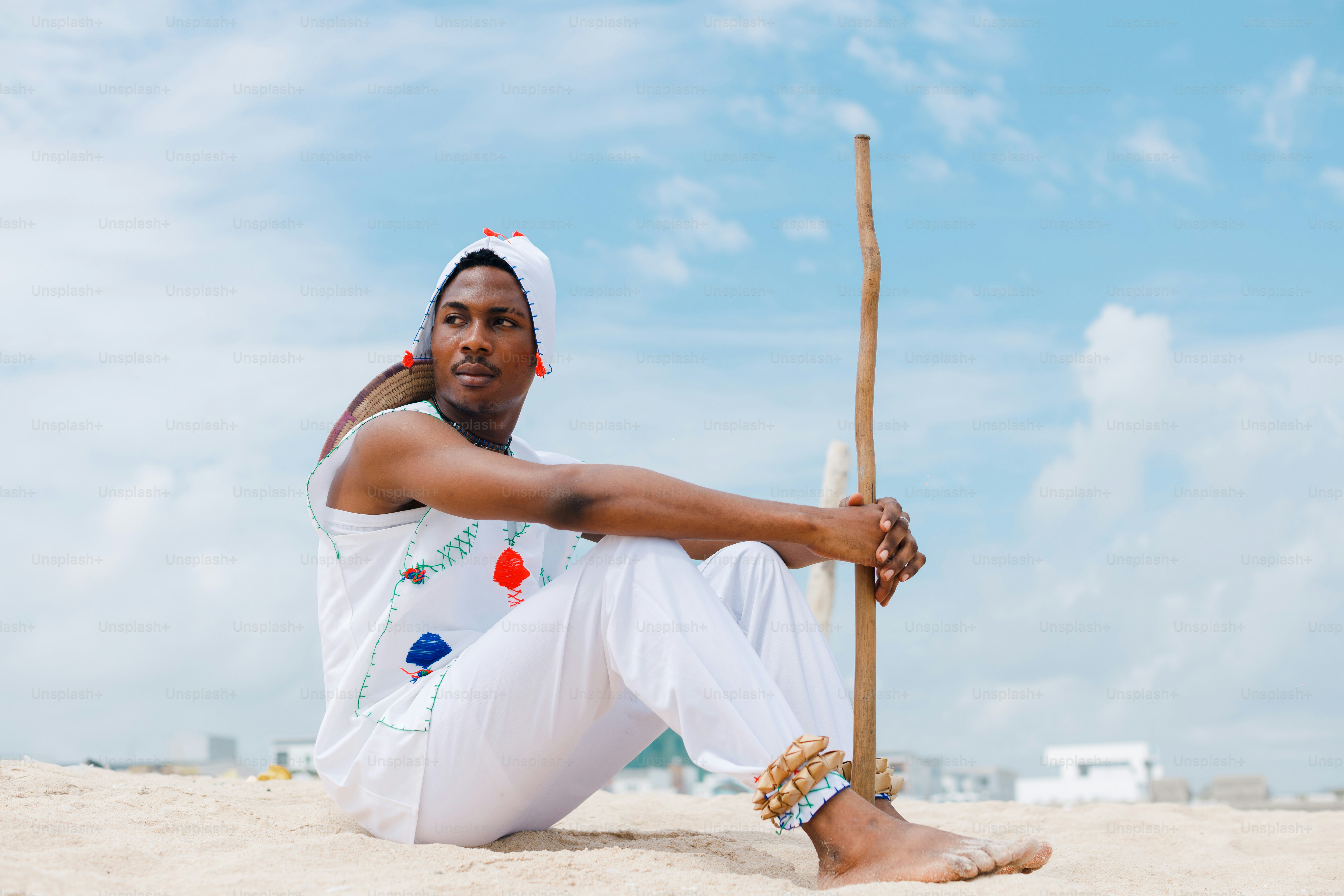 A man sitting in the sand with a stick