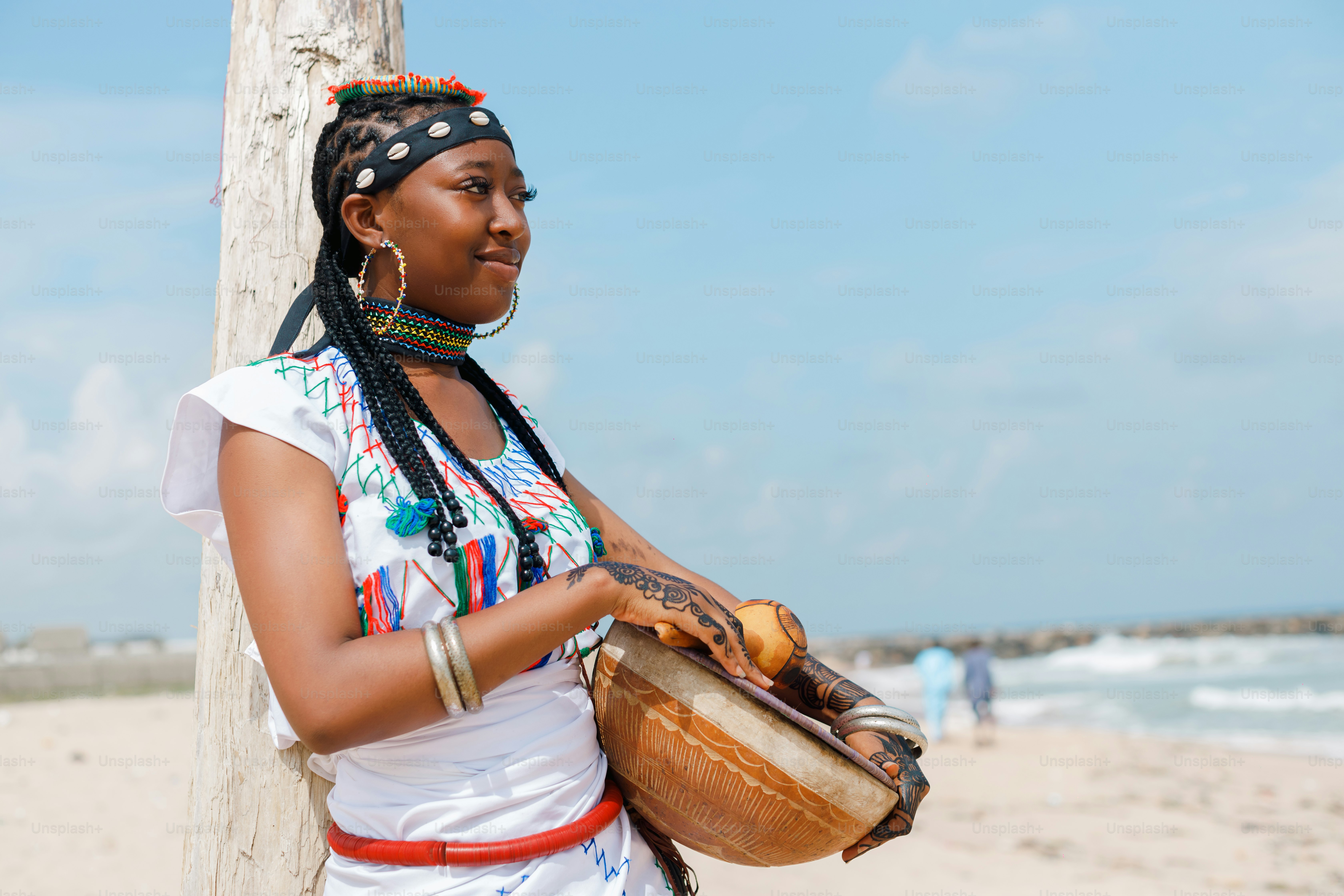 A woman standing on a beach holding a drum