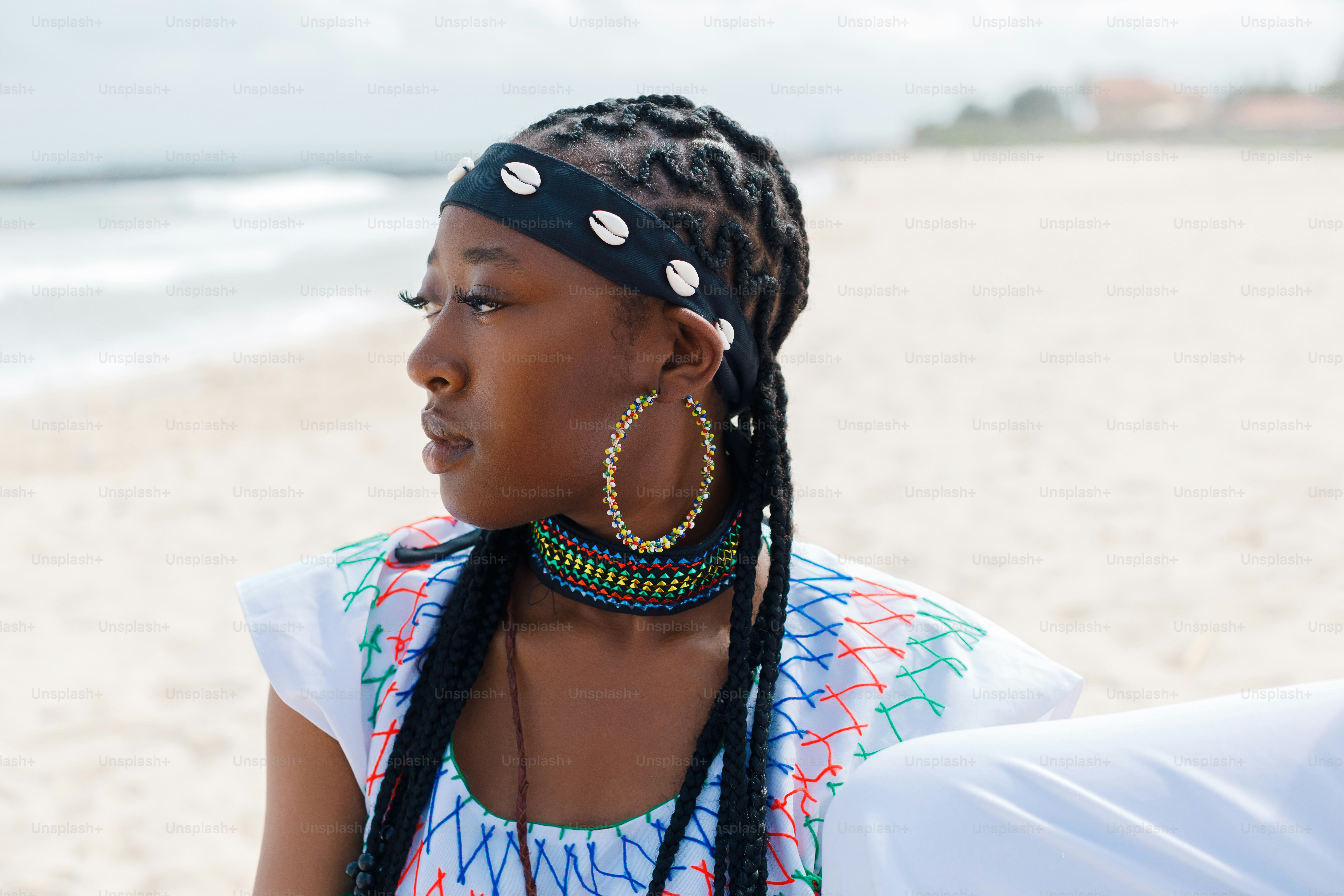 A woman sitting on the beach wearing a head scarf