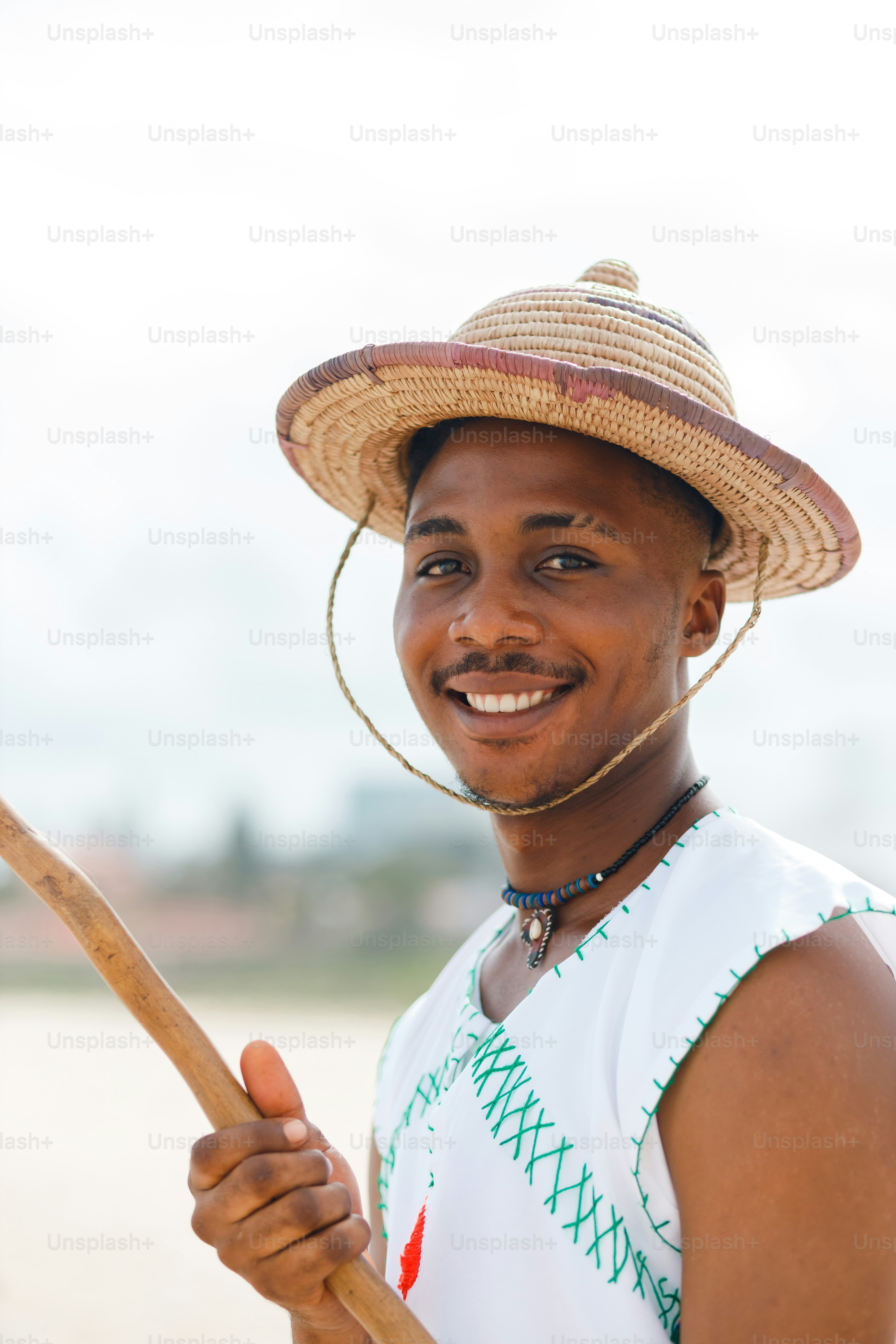 A man wearing a straw hat and holding a stick