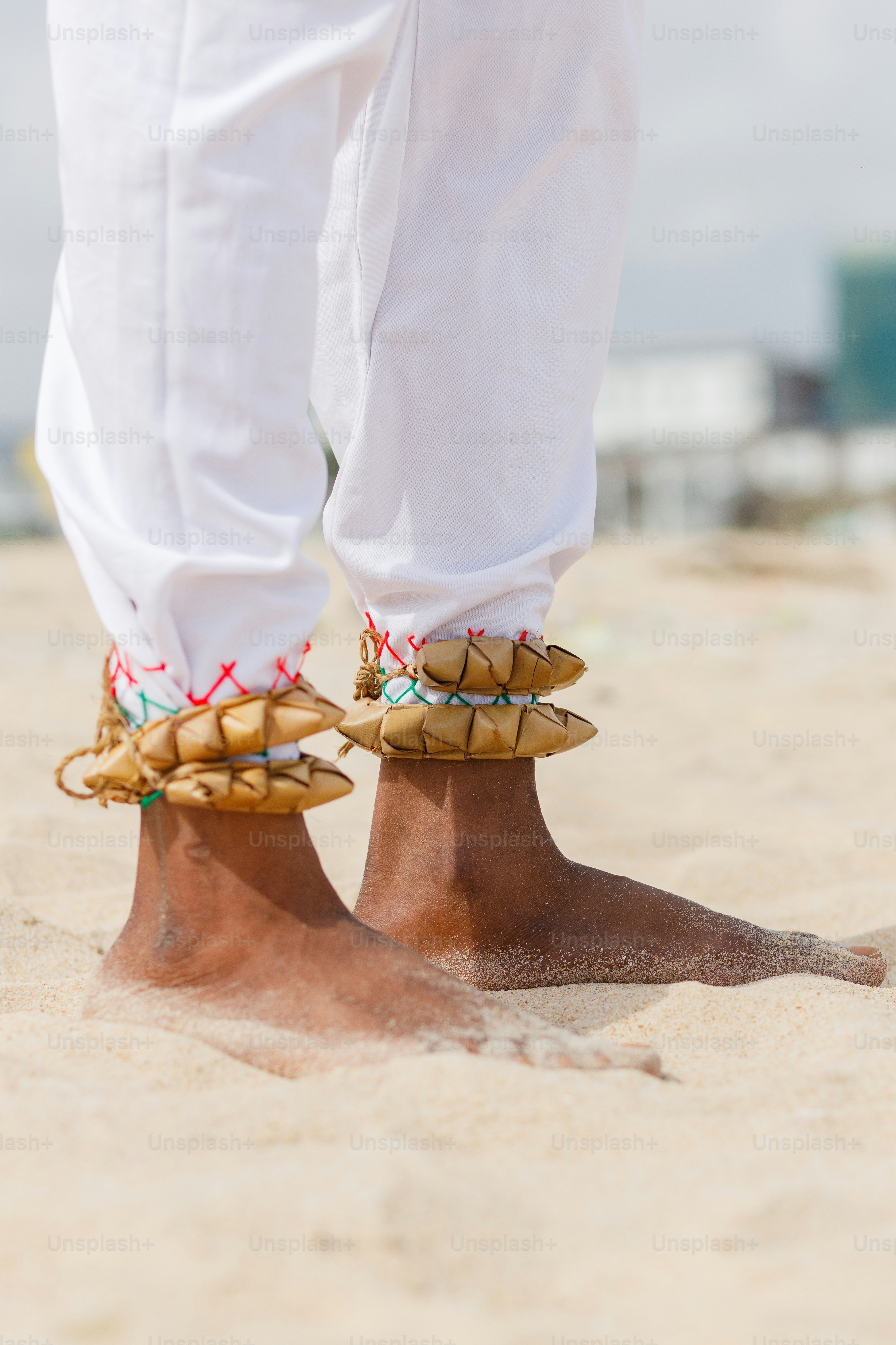A person standing on a sandy beach wearing sandals