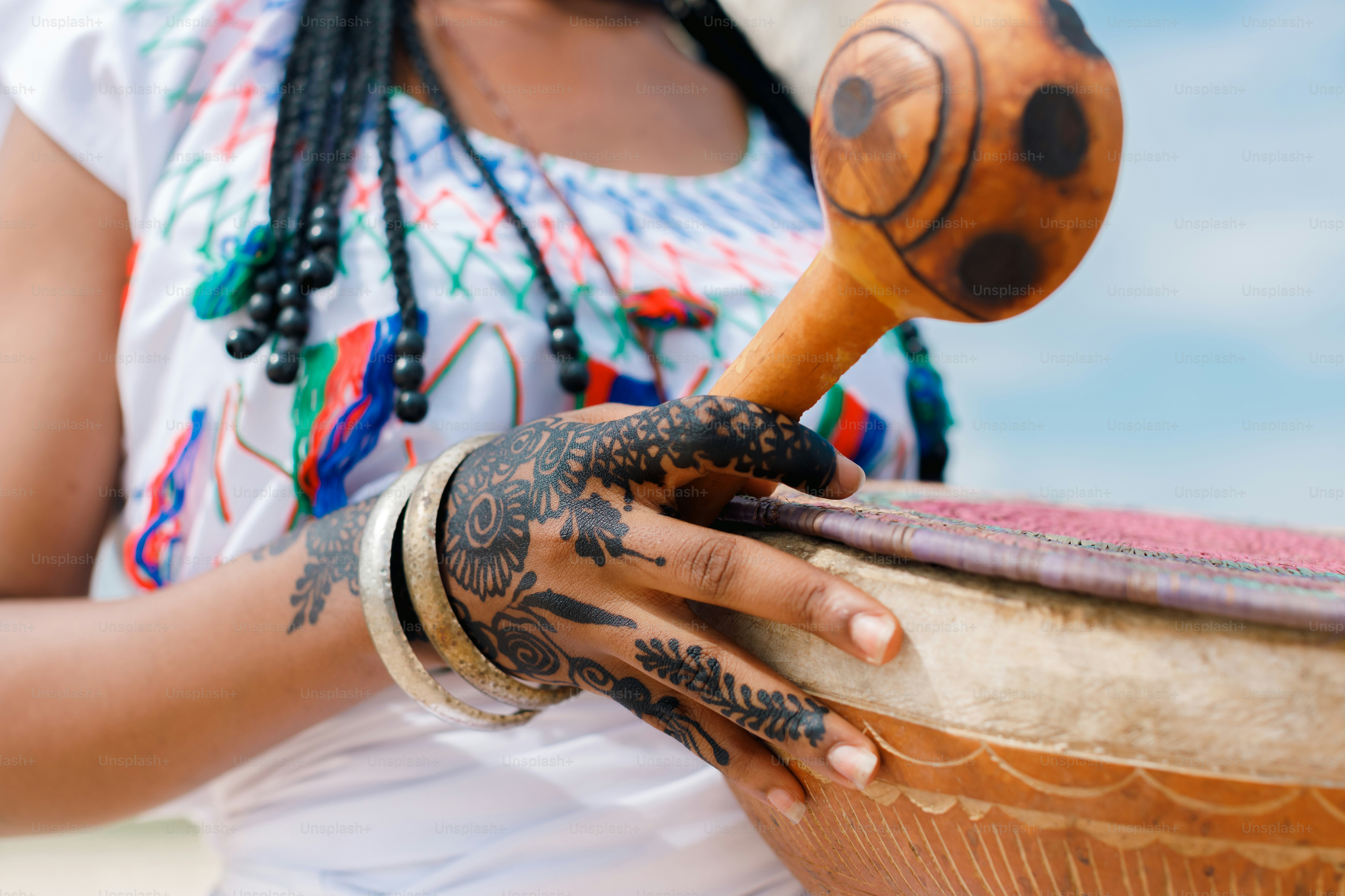 A woman with dreadlocks is playing a drum