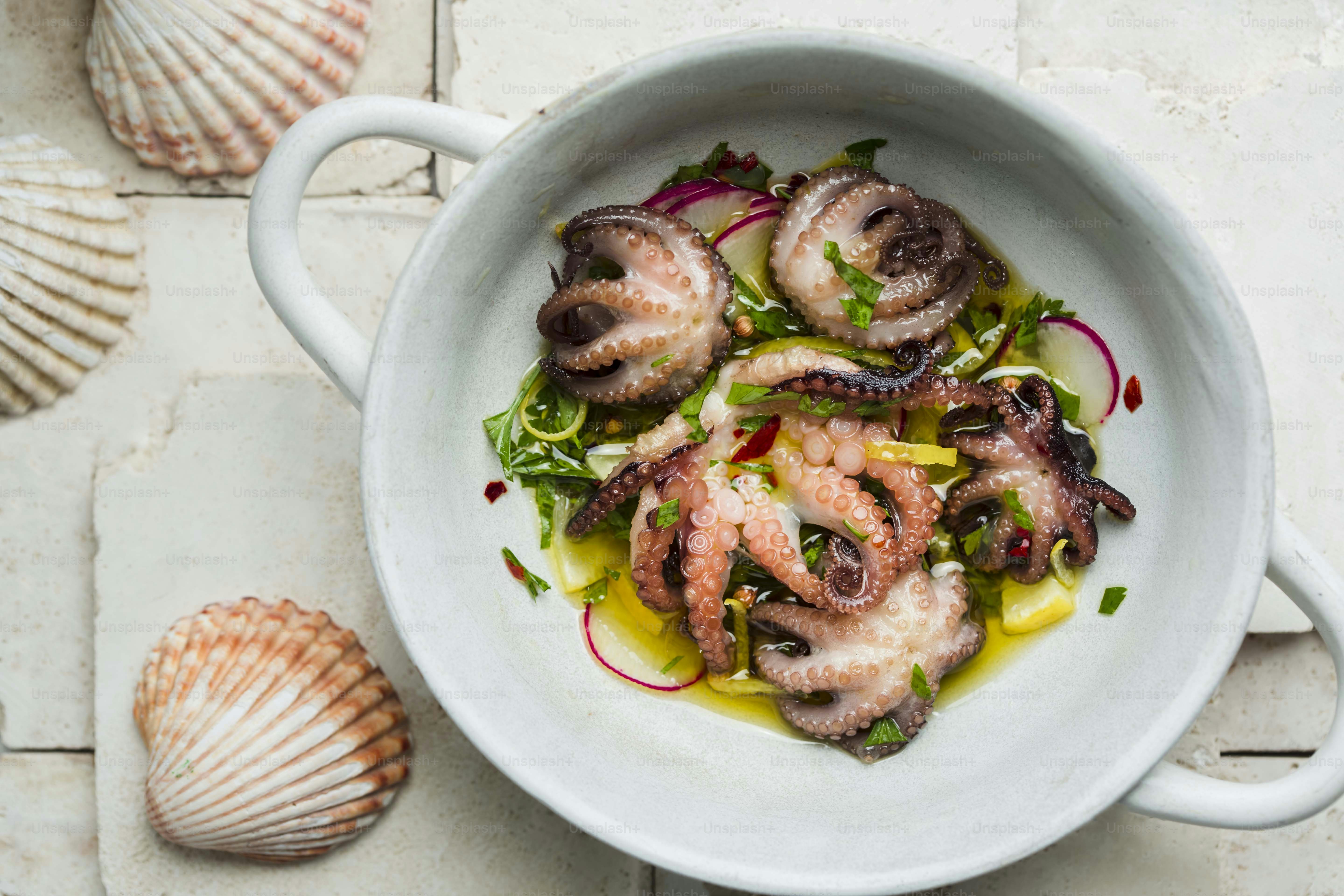 A white bowl filled with octopus on top of a table