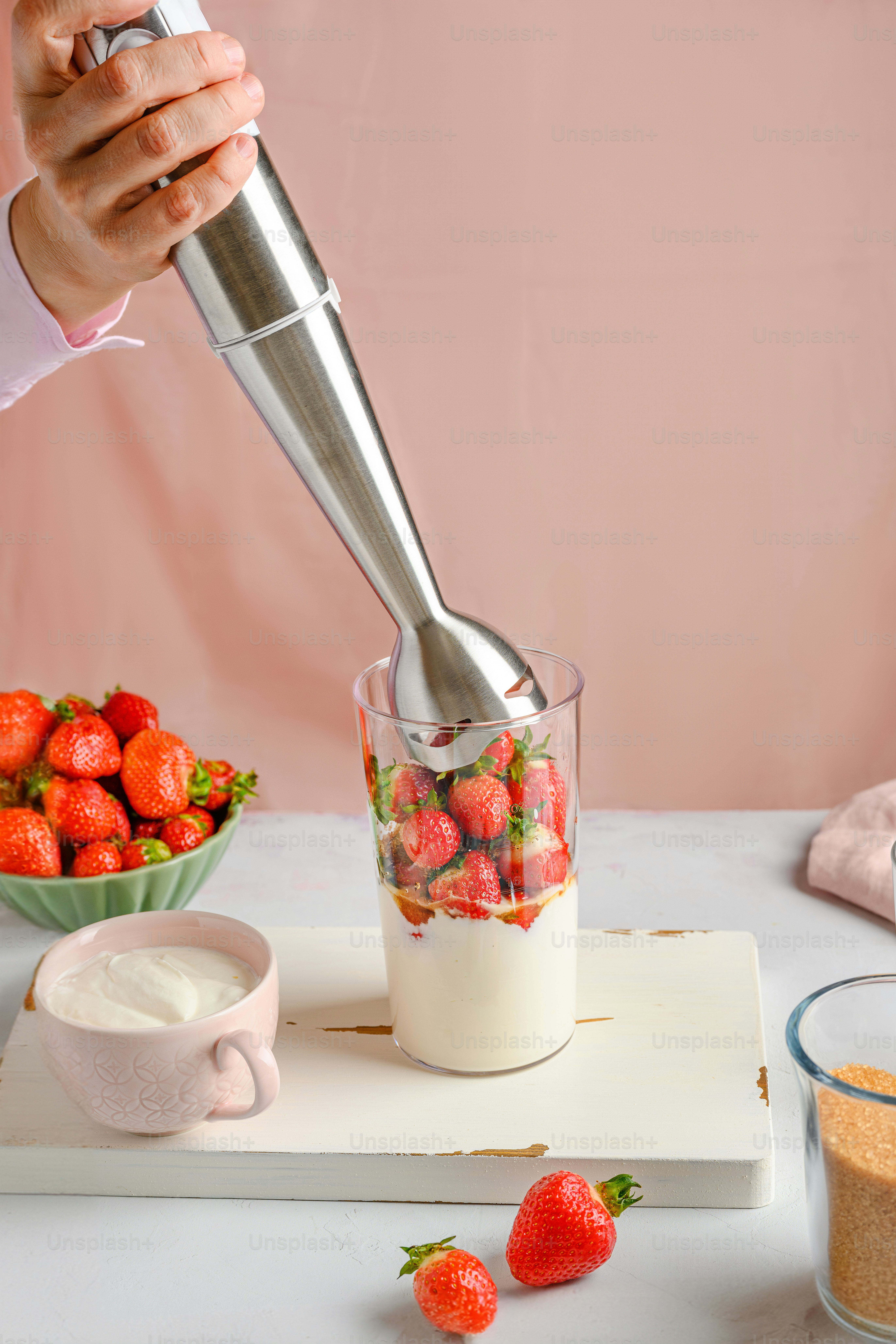A person is mixing strawberries in a blender