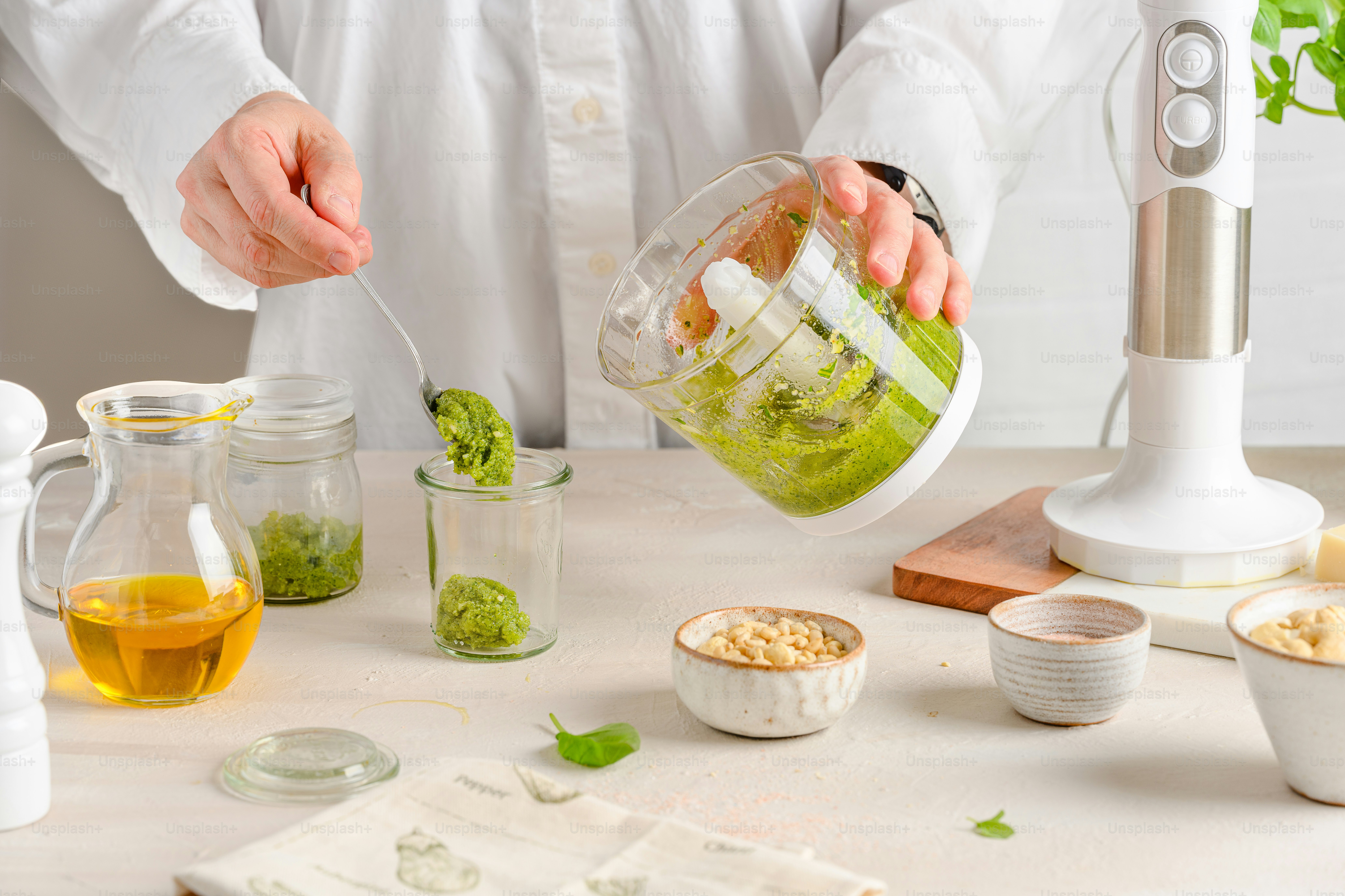 A person pouring something into a blender on a table