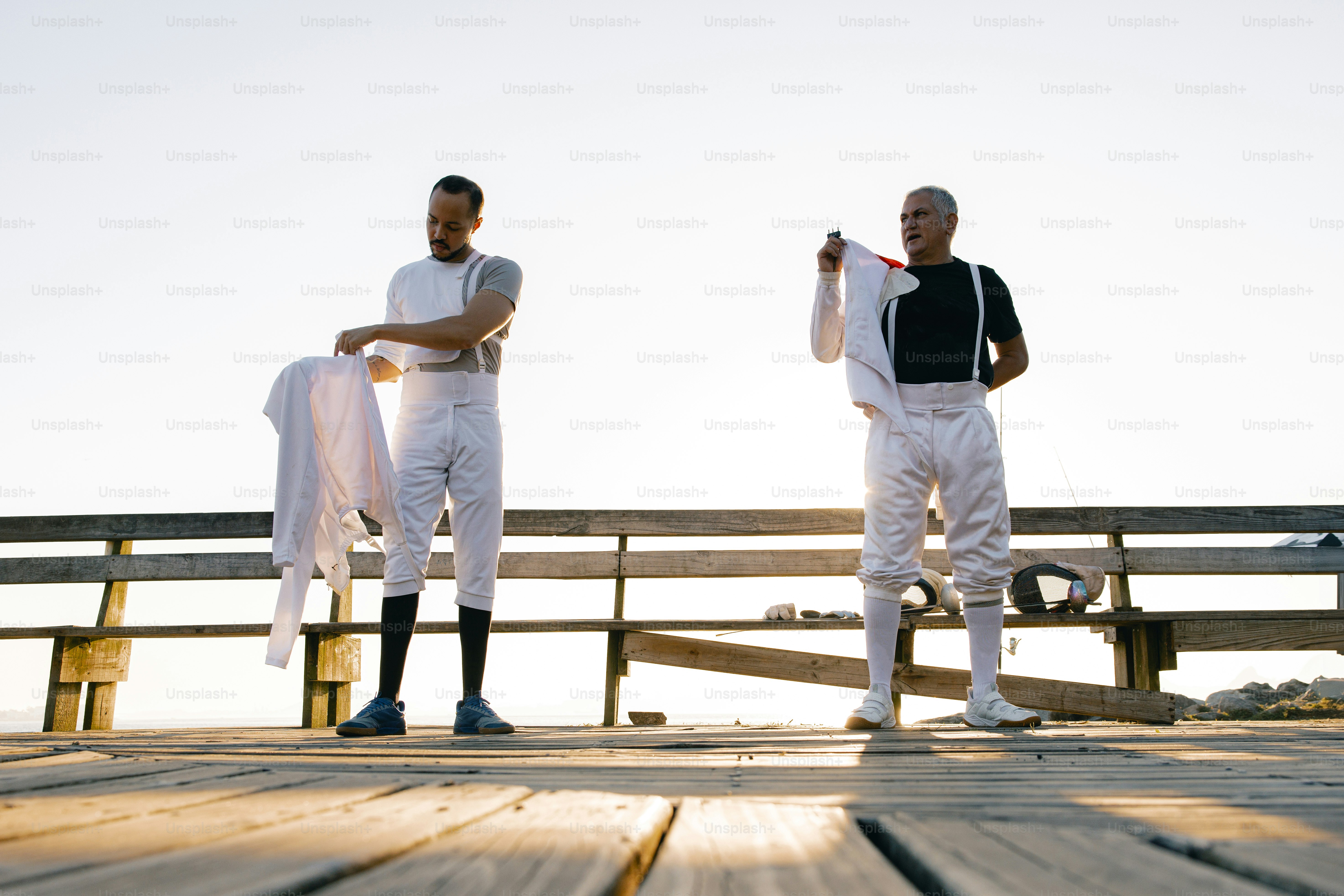 A couple of men standing on top of a wooden pier