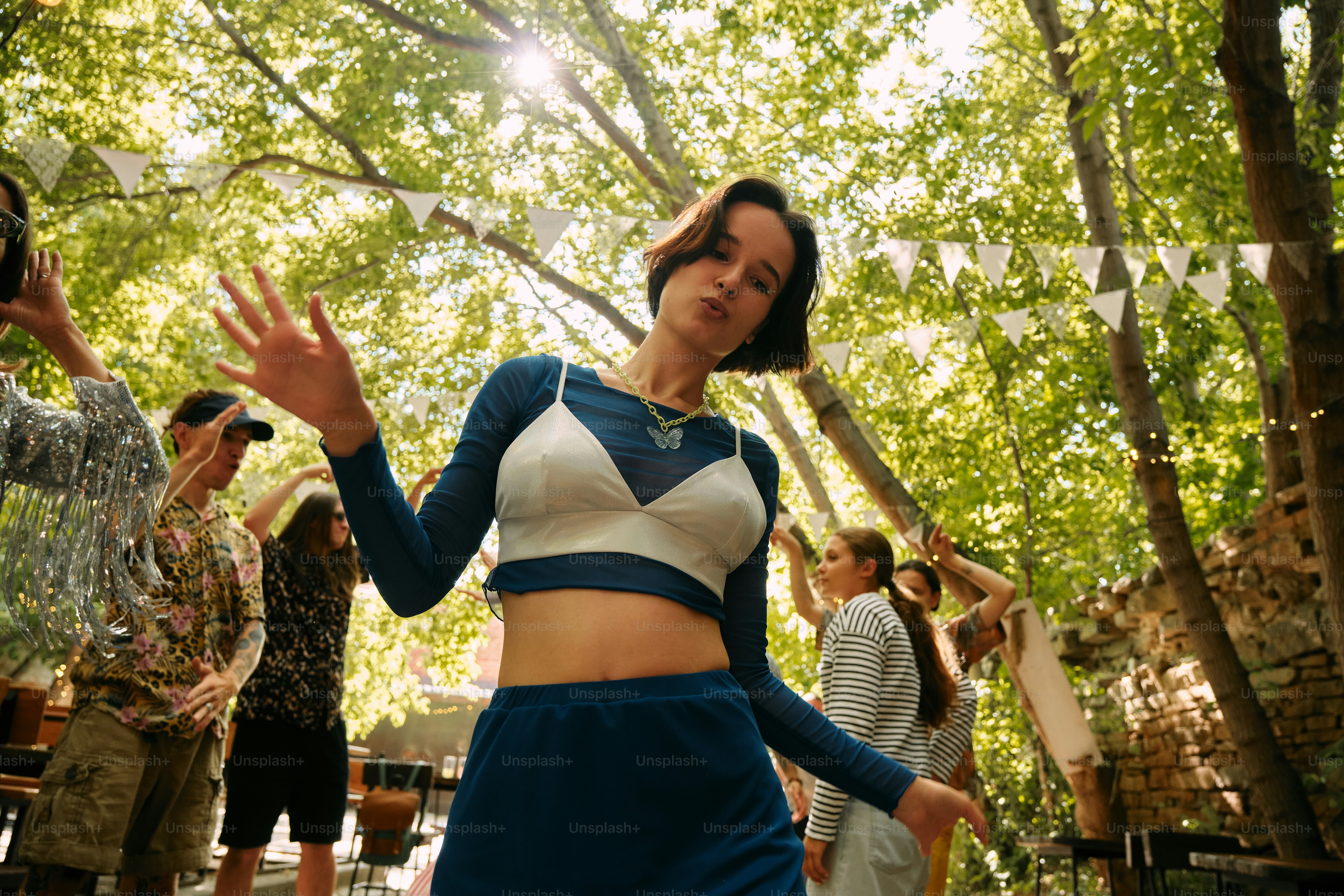A woman in a blue and white top dancing in the woods