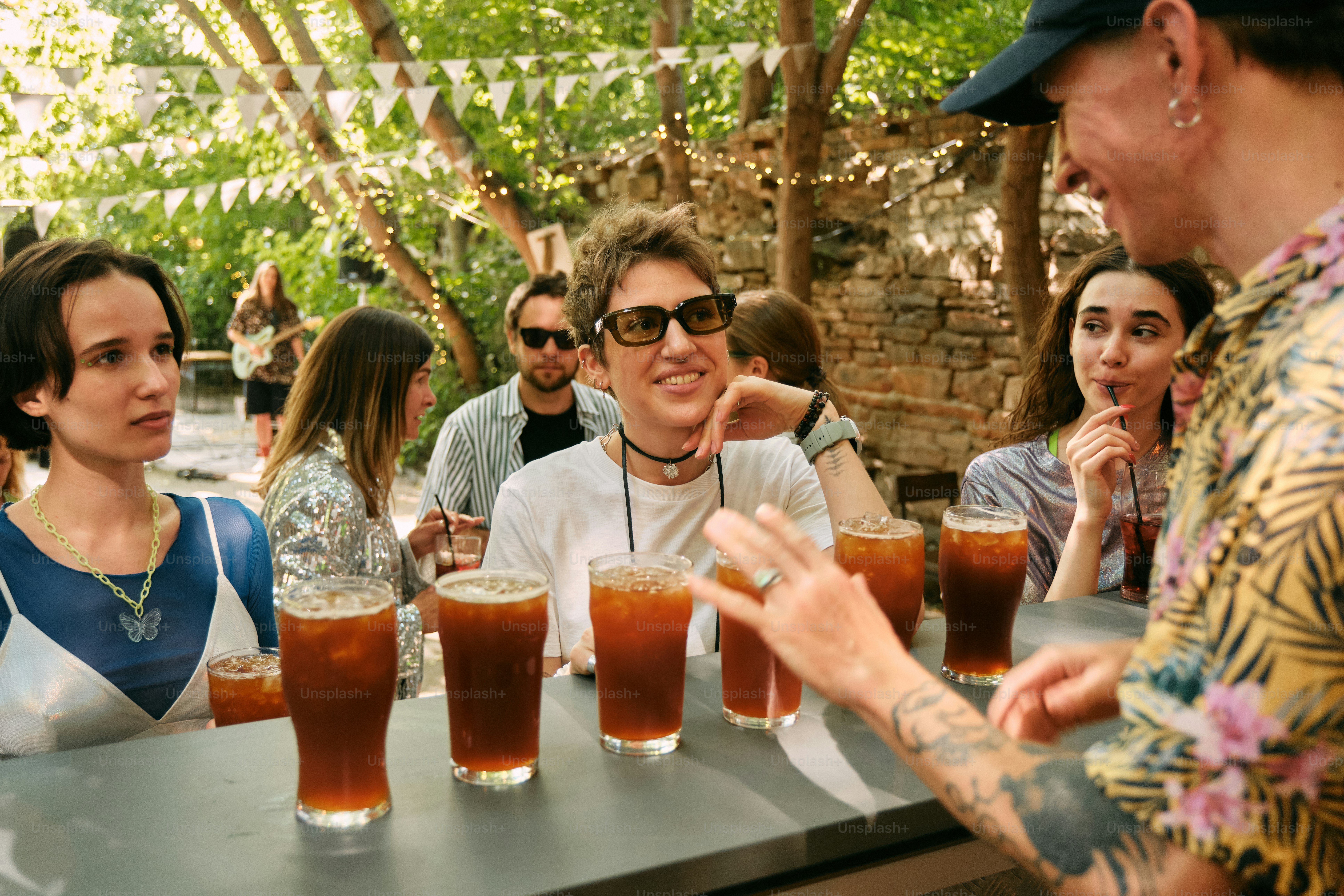 A group of people sitting around a table with beers photo – Festival ...