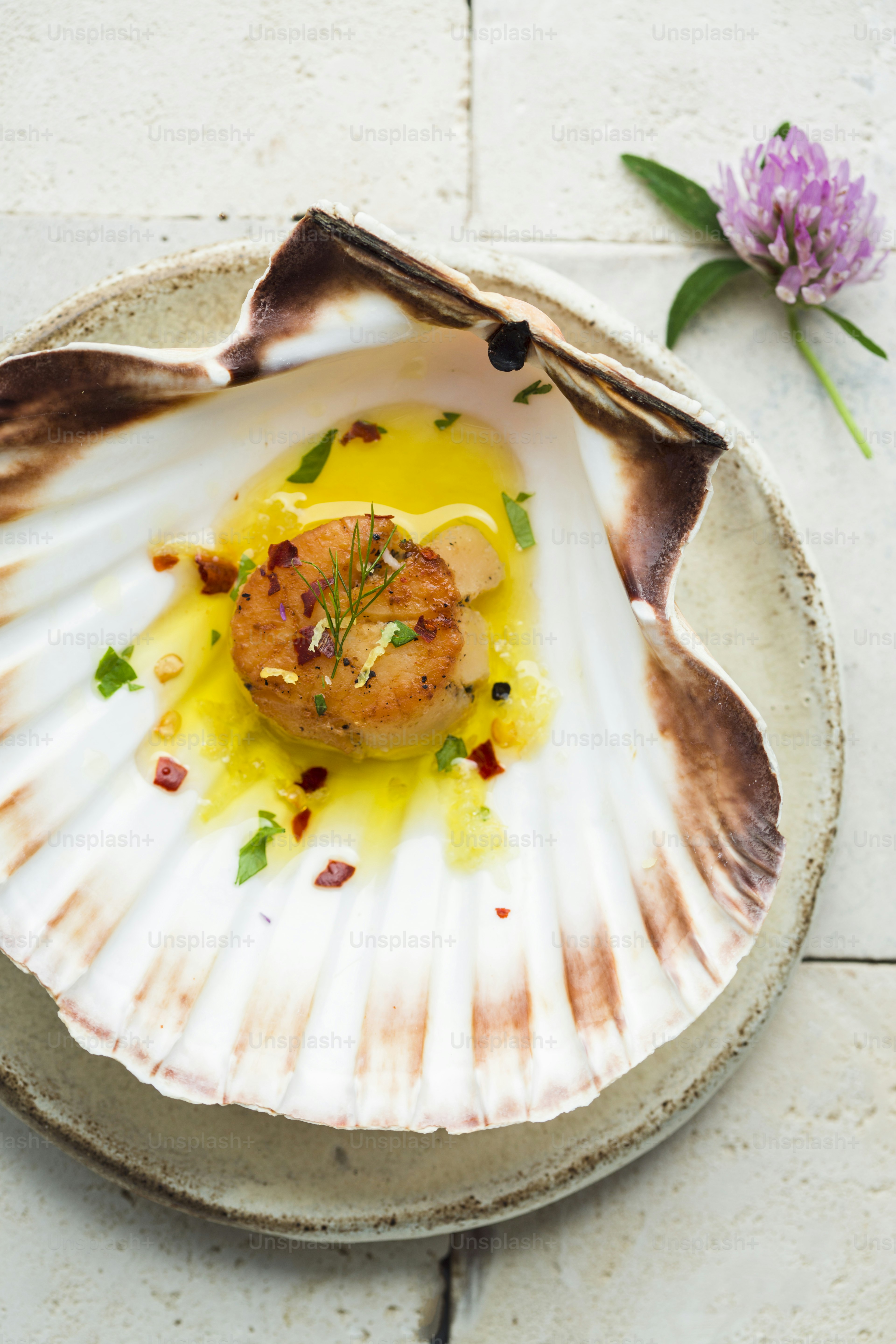 A scallop dish on a plate with a flower on the side