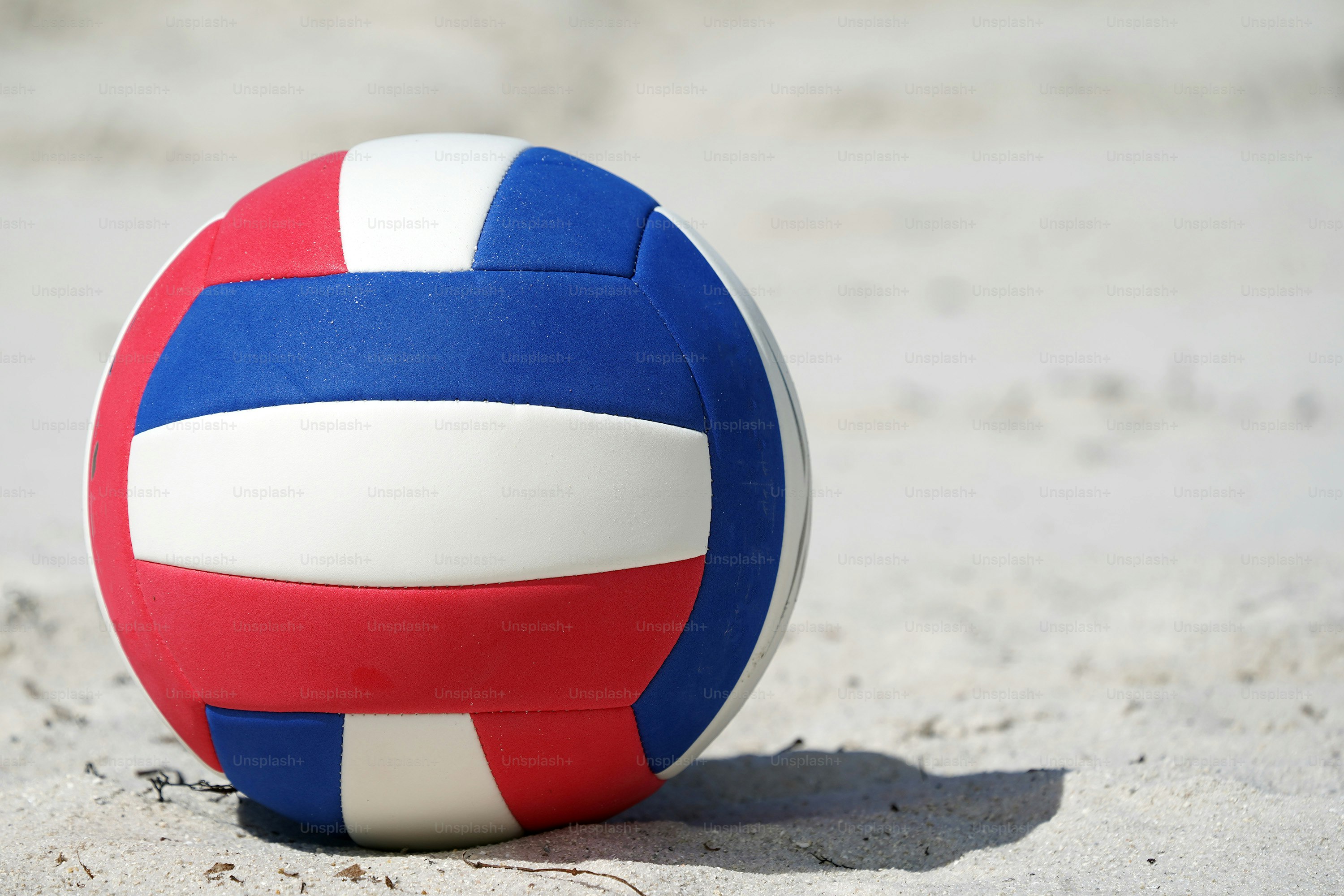 Bola pantai merah, putih dan biru di atas pasir