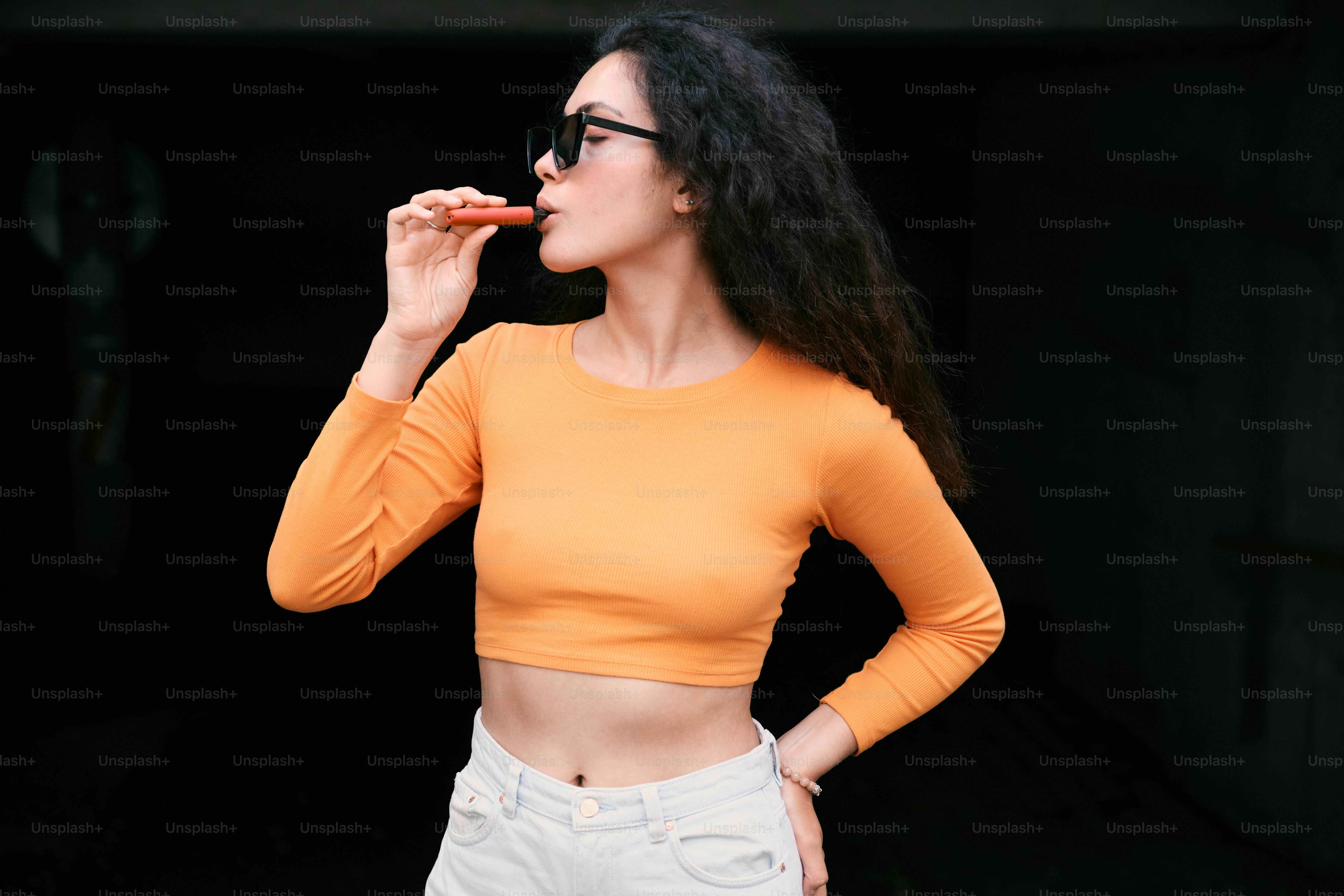 A woman in a yellow top is eating a piece of pizza