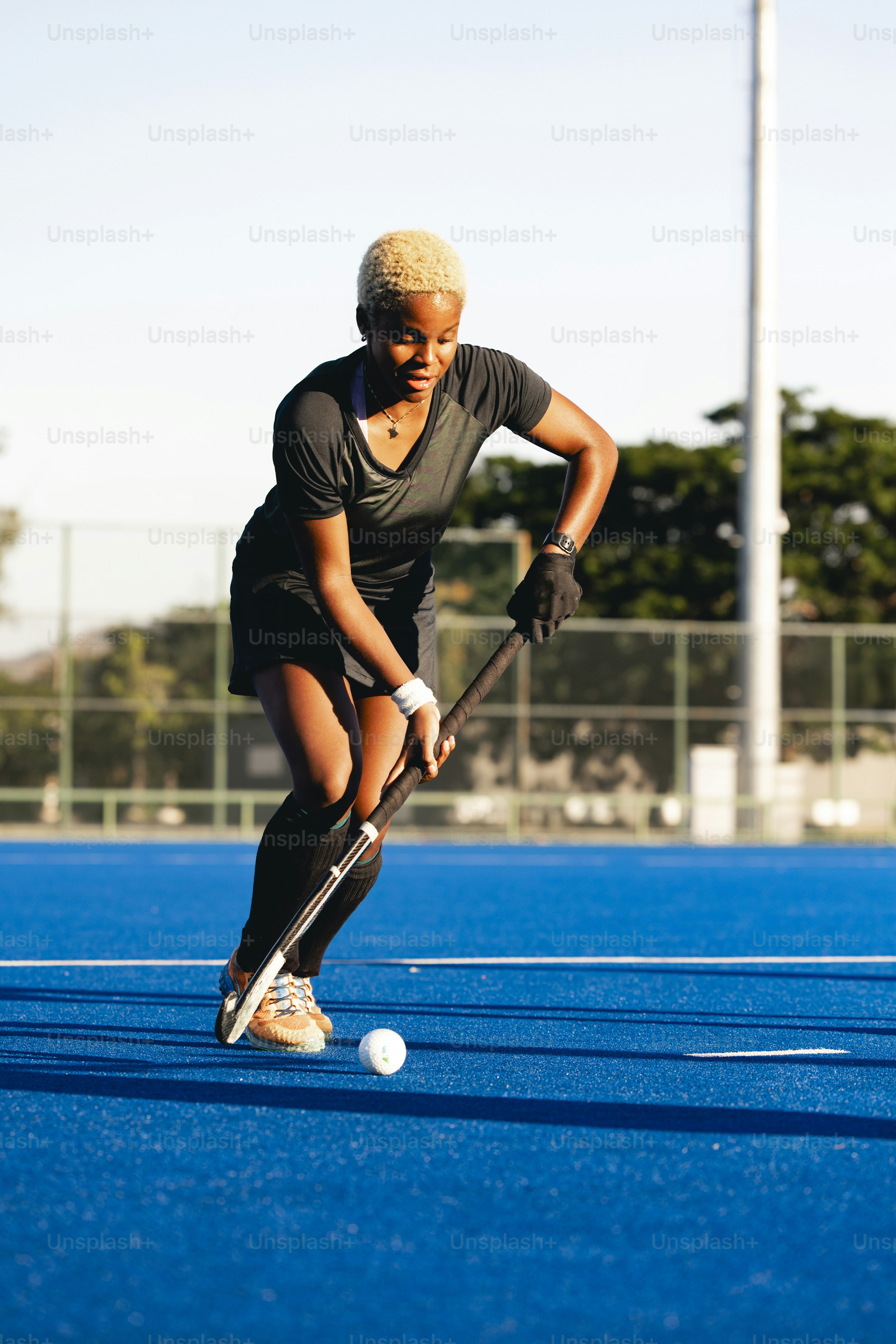 A woman playing field hockey on a sunny day