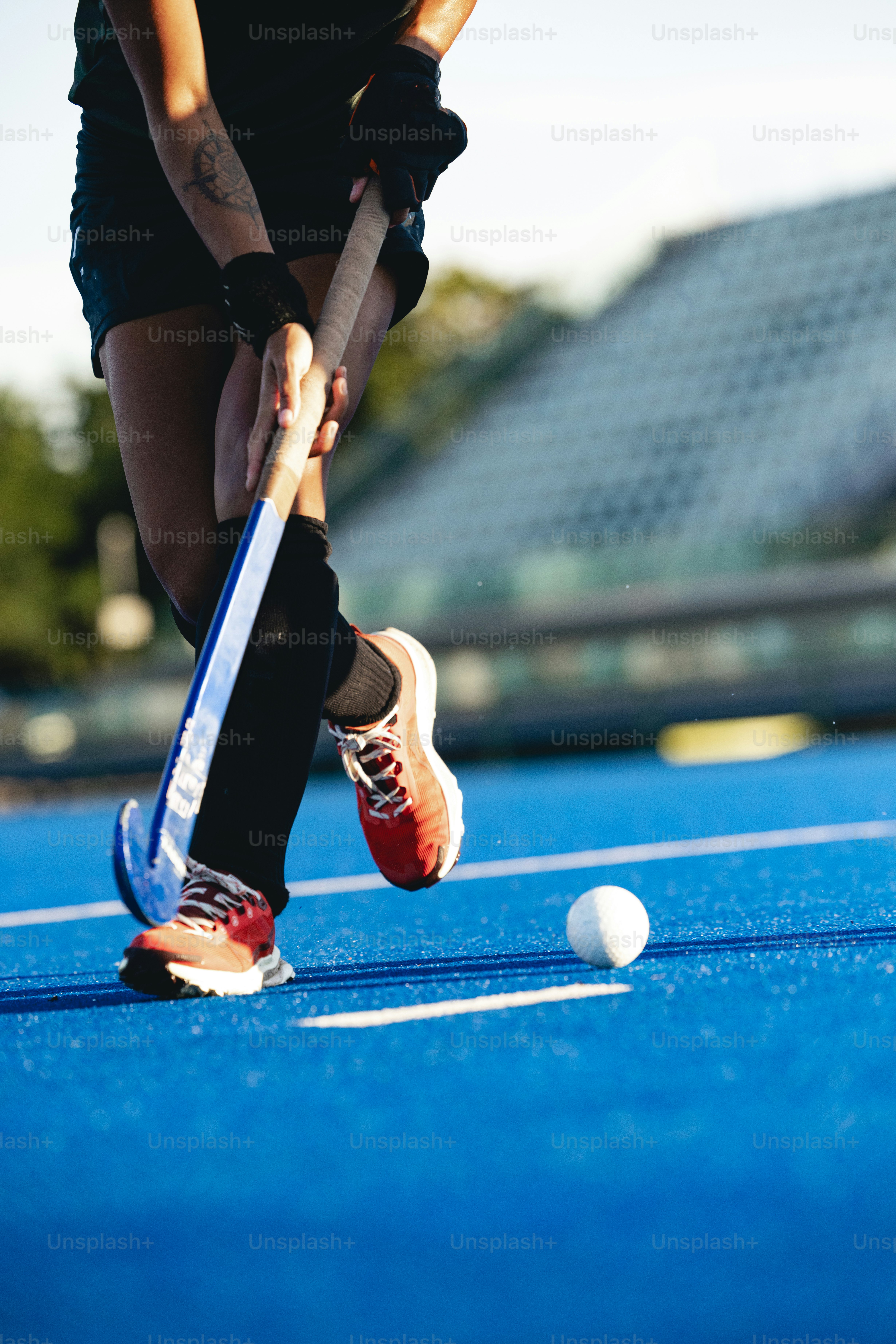 A woman playing field hockey on a blue court