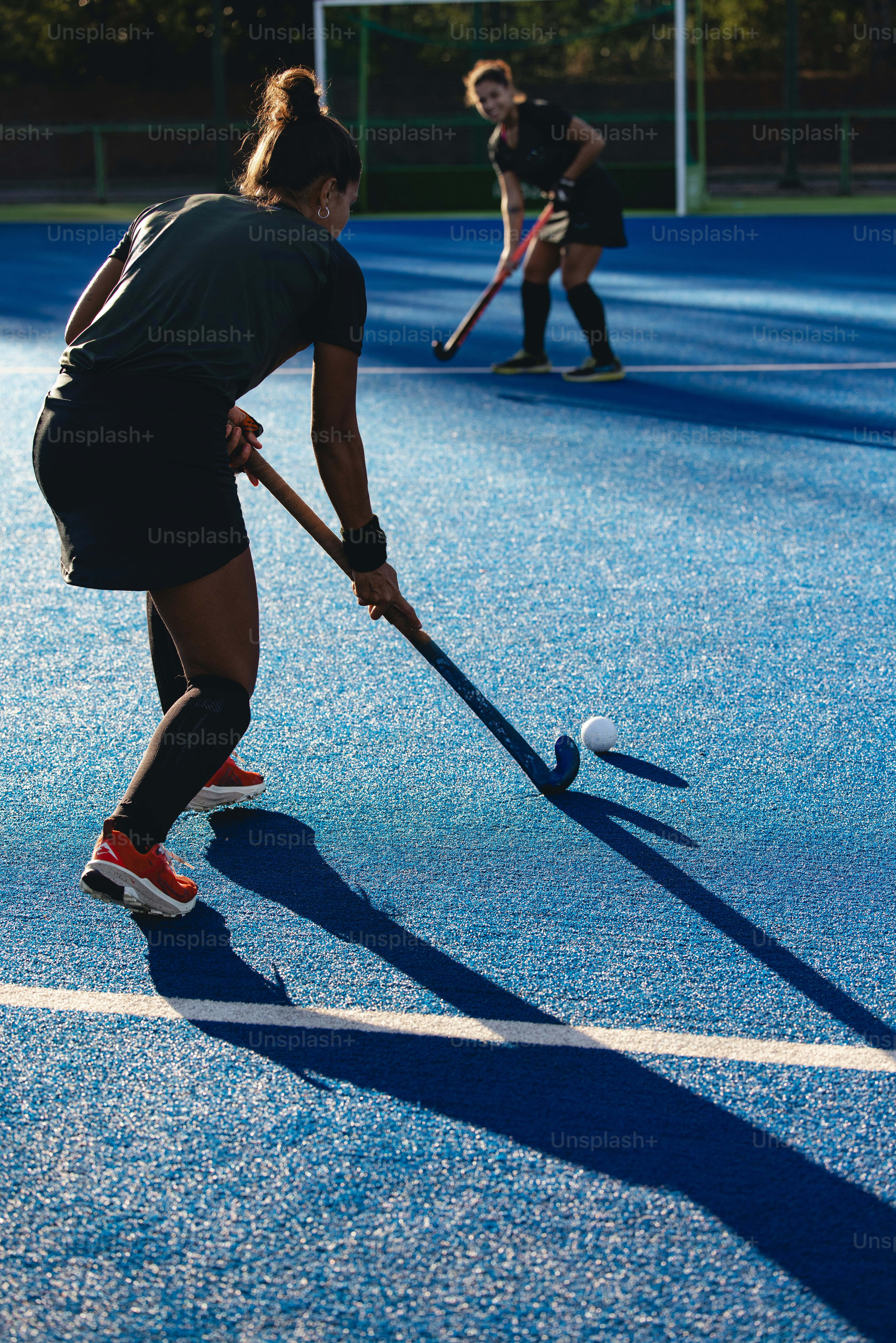 A couple of women playing a game of field hockey
