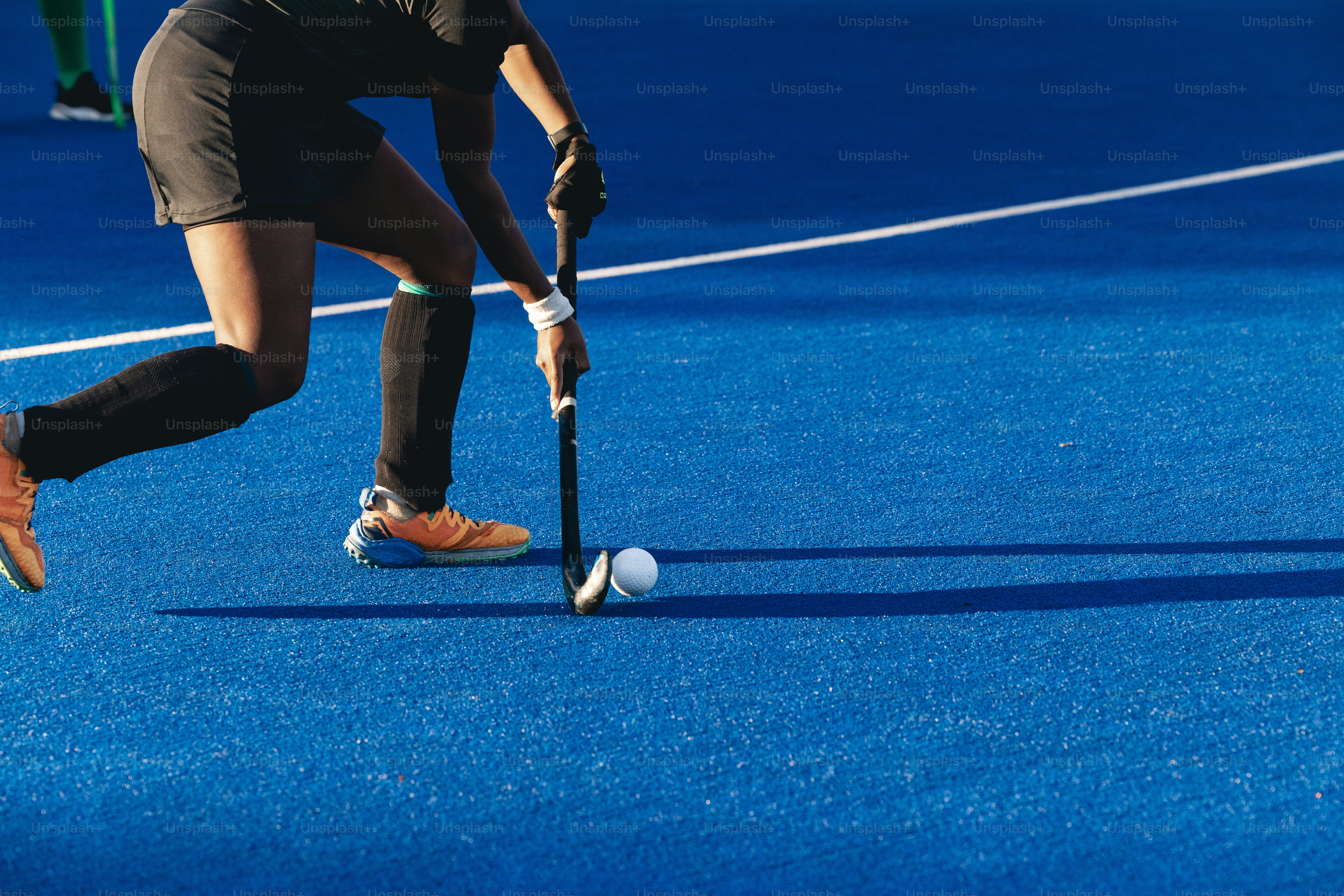 Une femme jouant au hockey sur gazon sur un terrain bleu