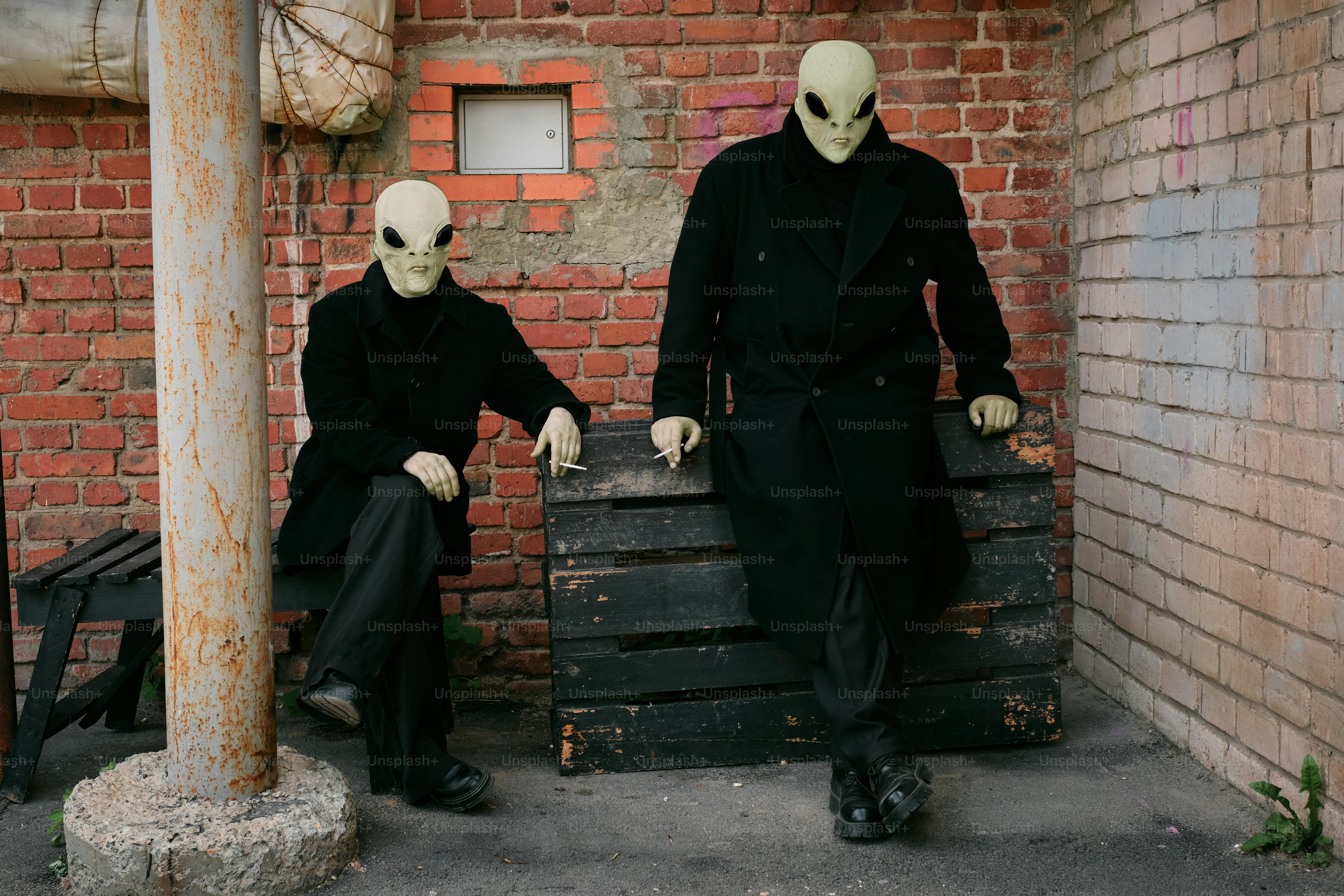 A couple of men sitting next to each other in front of a brick building