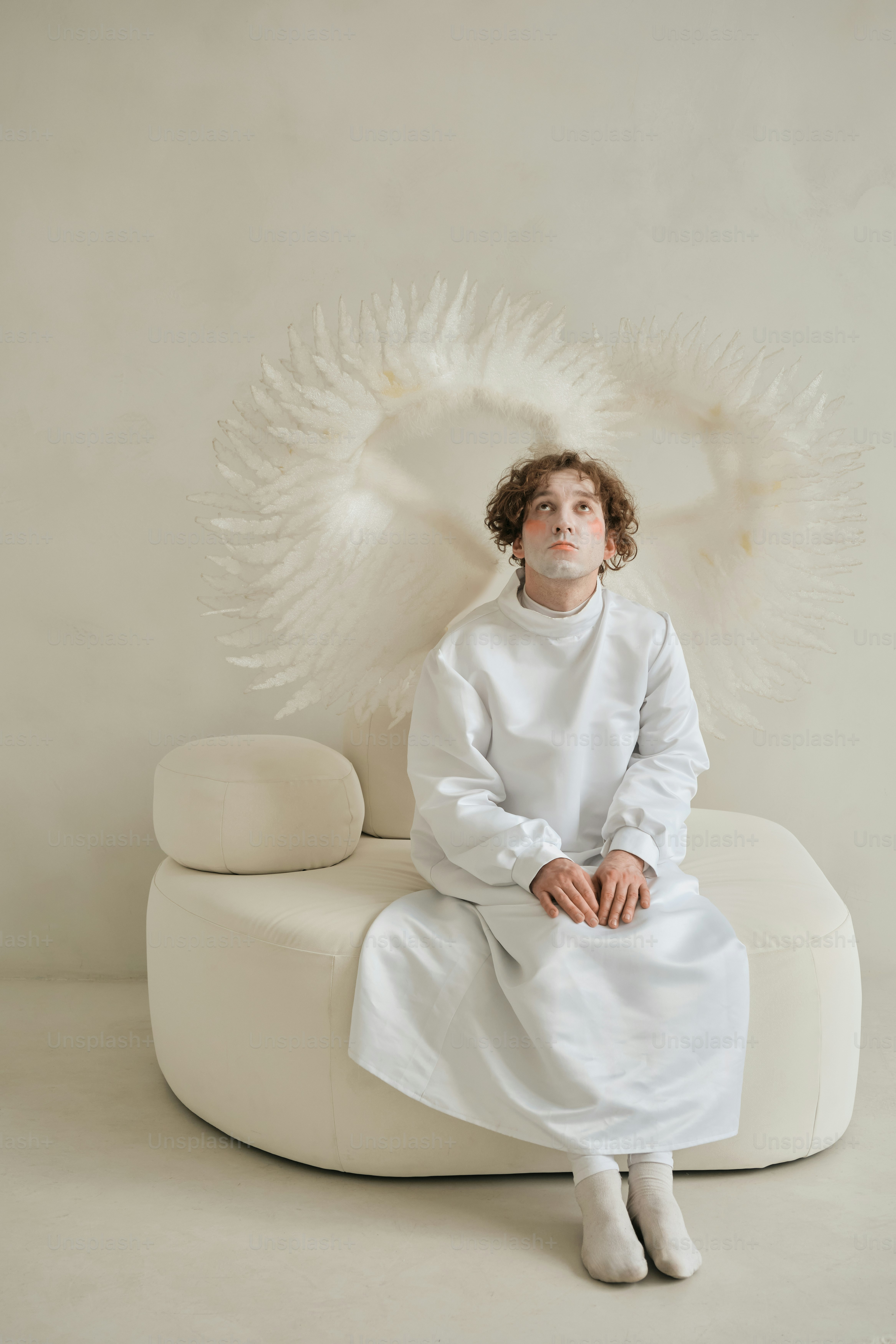 Una mujer sentada en una silla blanca con alas de ángel blancas detrás de ella