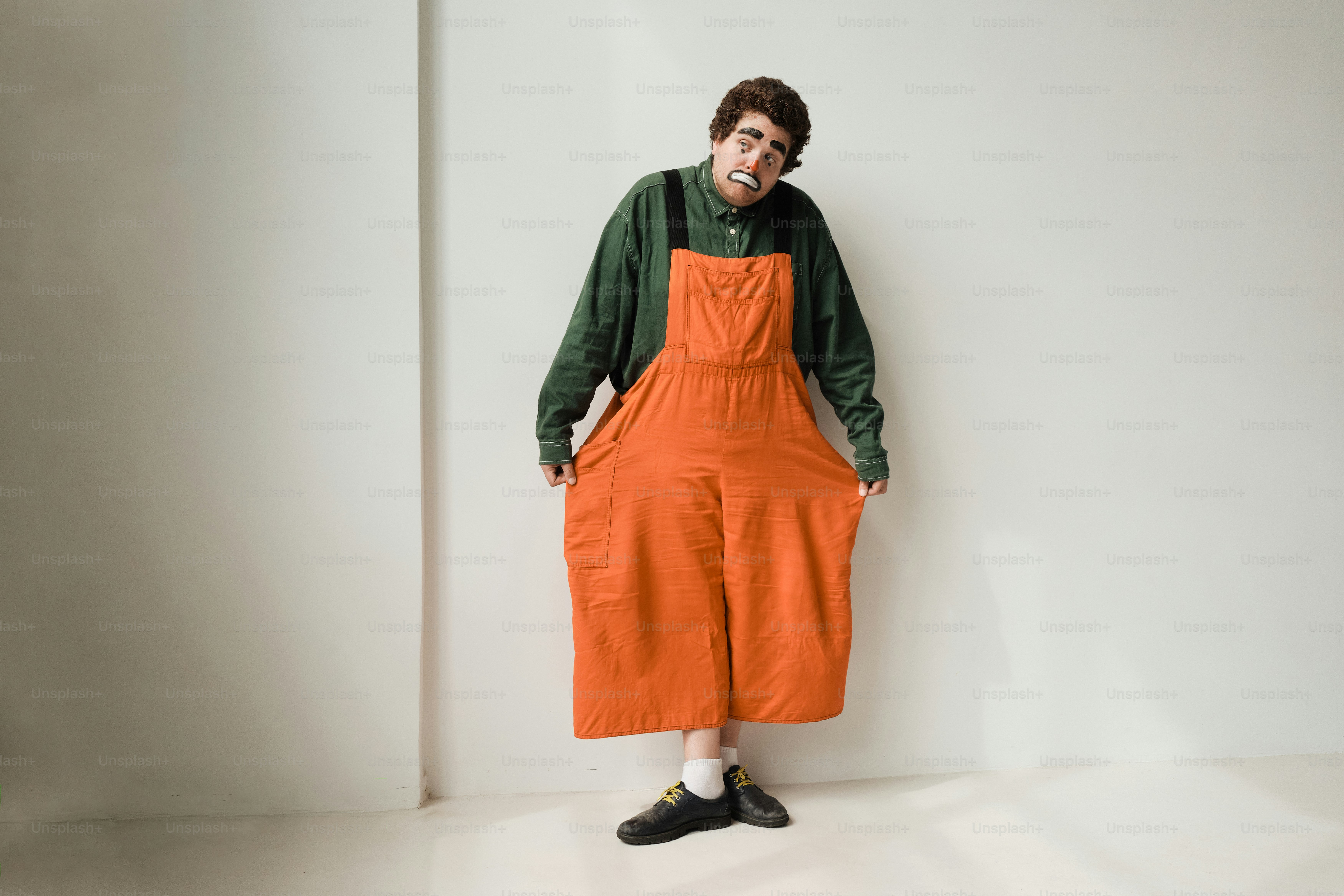 A man in an orange jumpsuit standing against a white wall