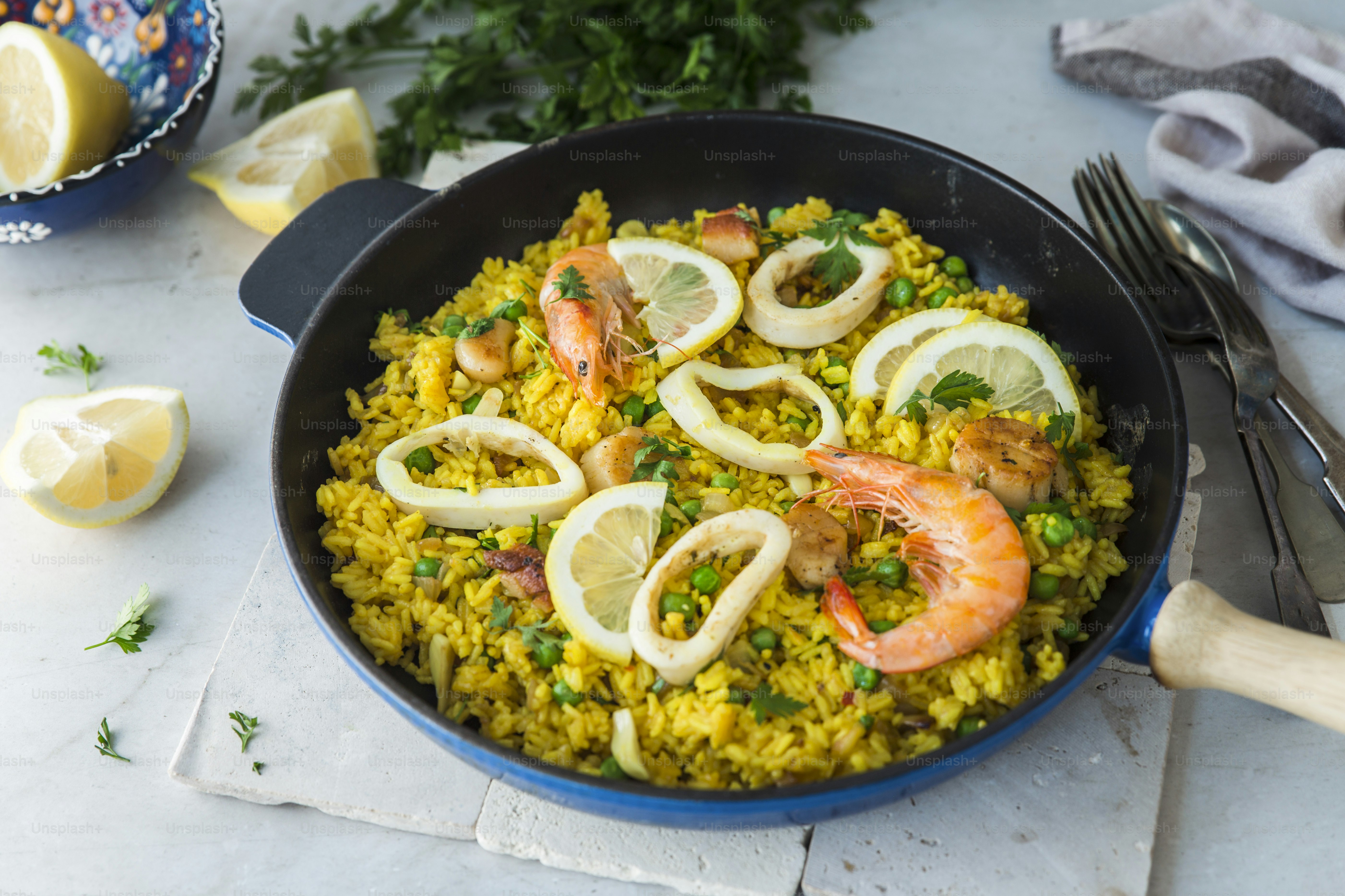A pan filled with shrimp and rice next to lemon wedges