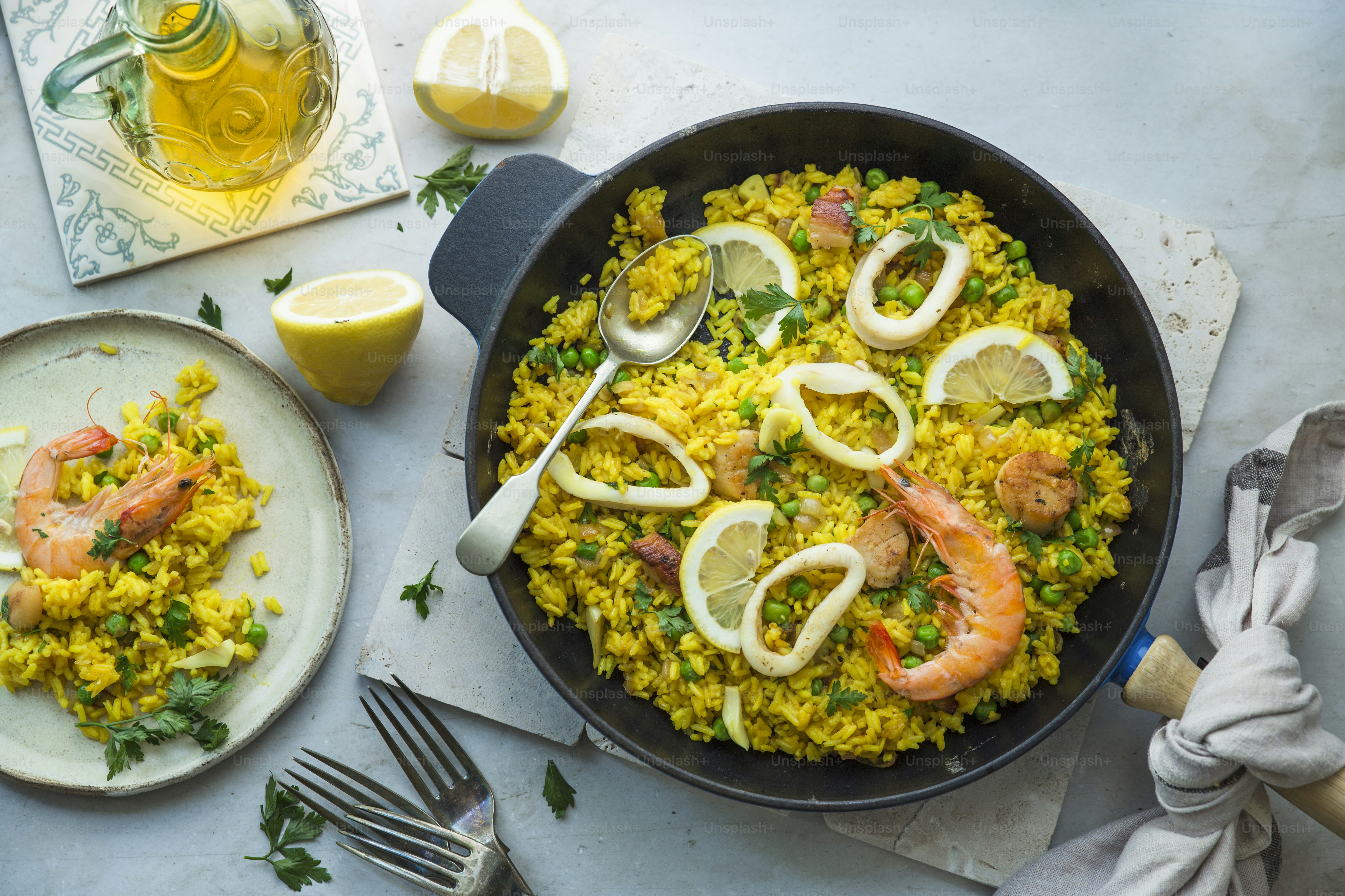 A pan filled with shrimp and rice next to a plate of lemons