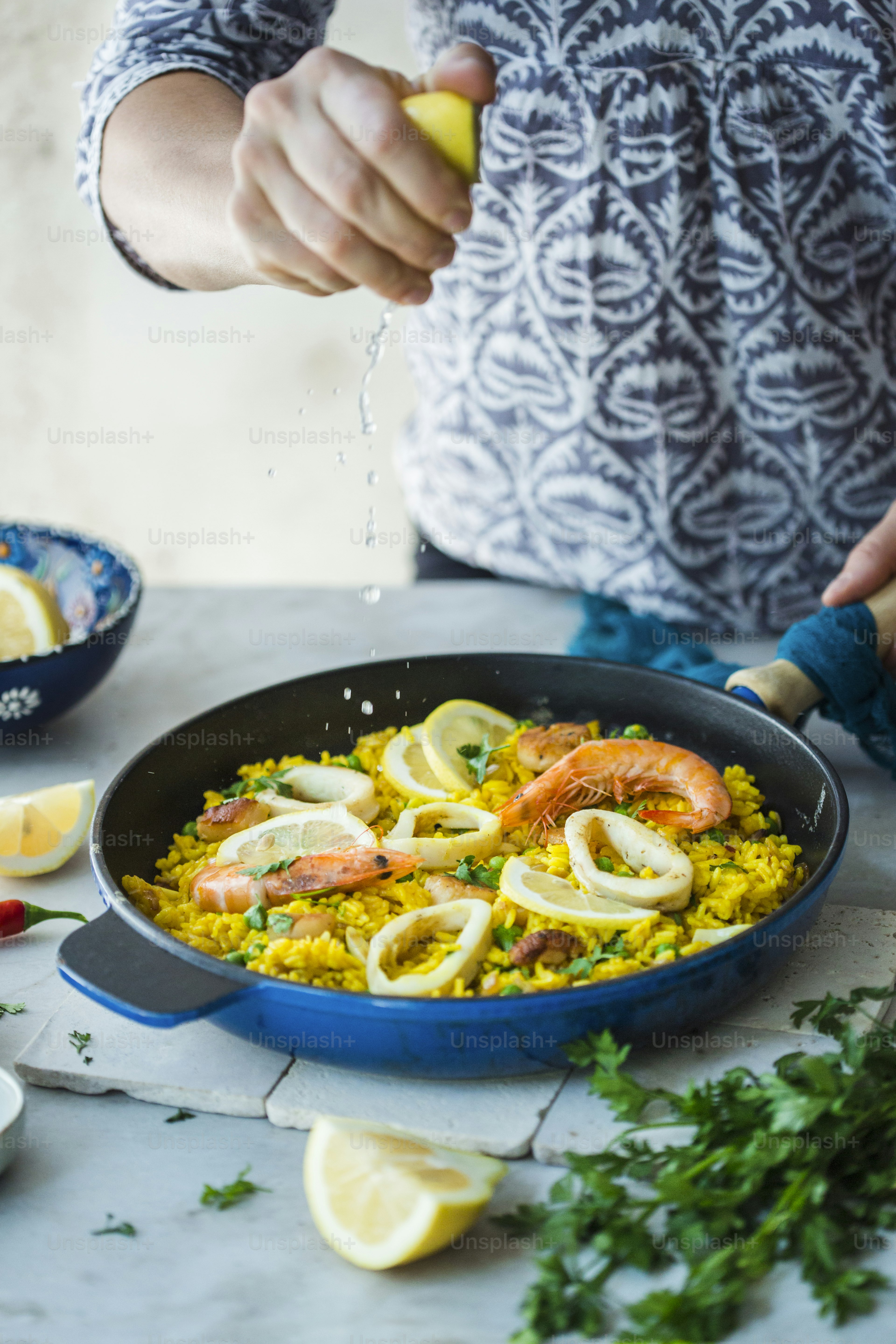 A person sprinkling lemons on a dish of food