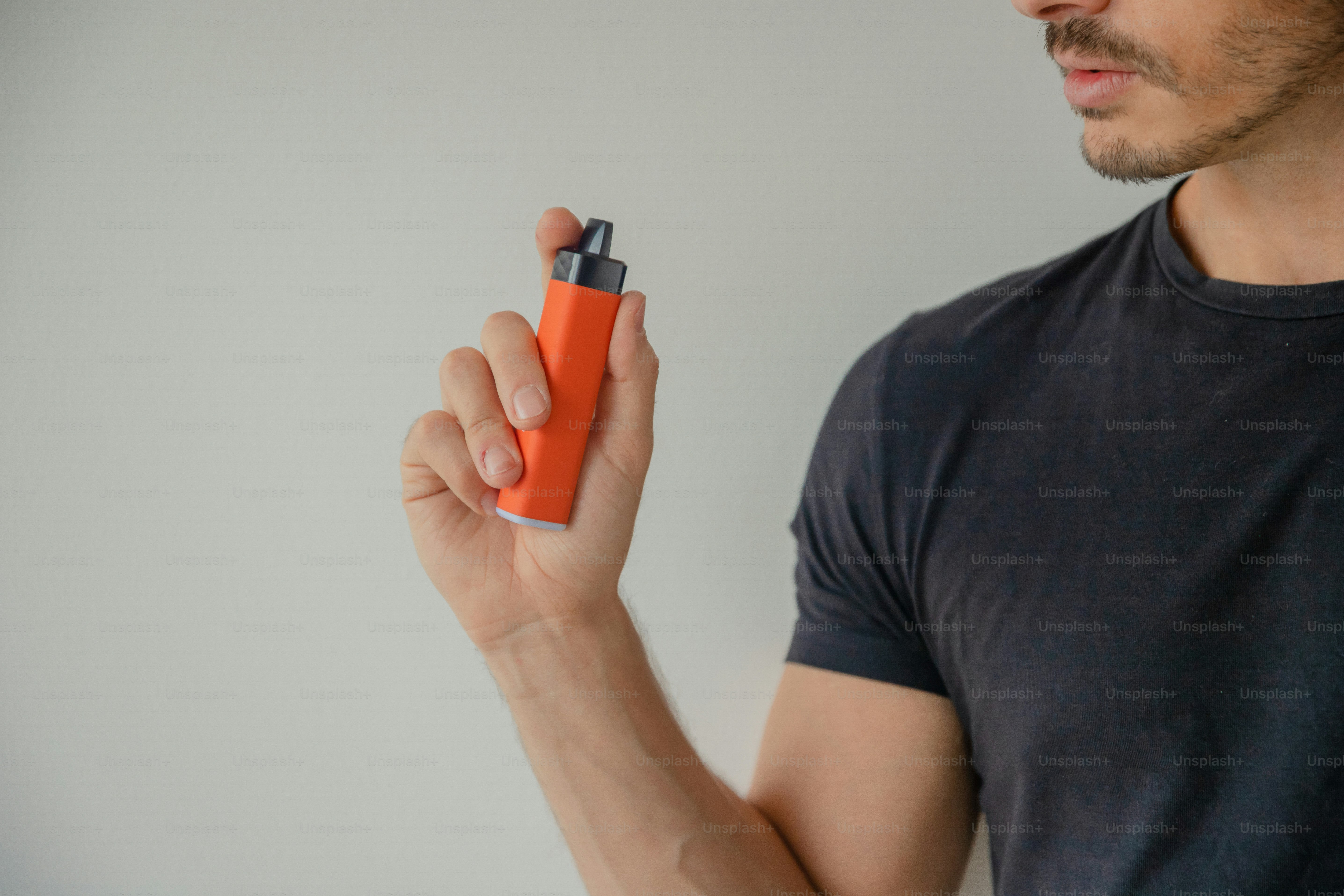 A man holding an orange lighter in his right hand