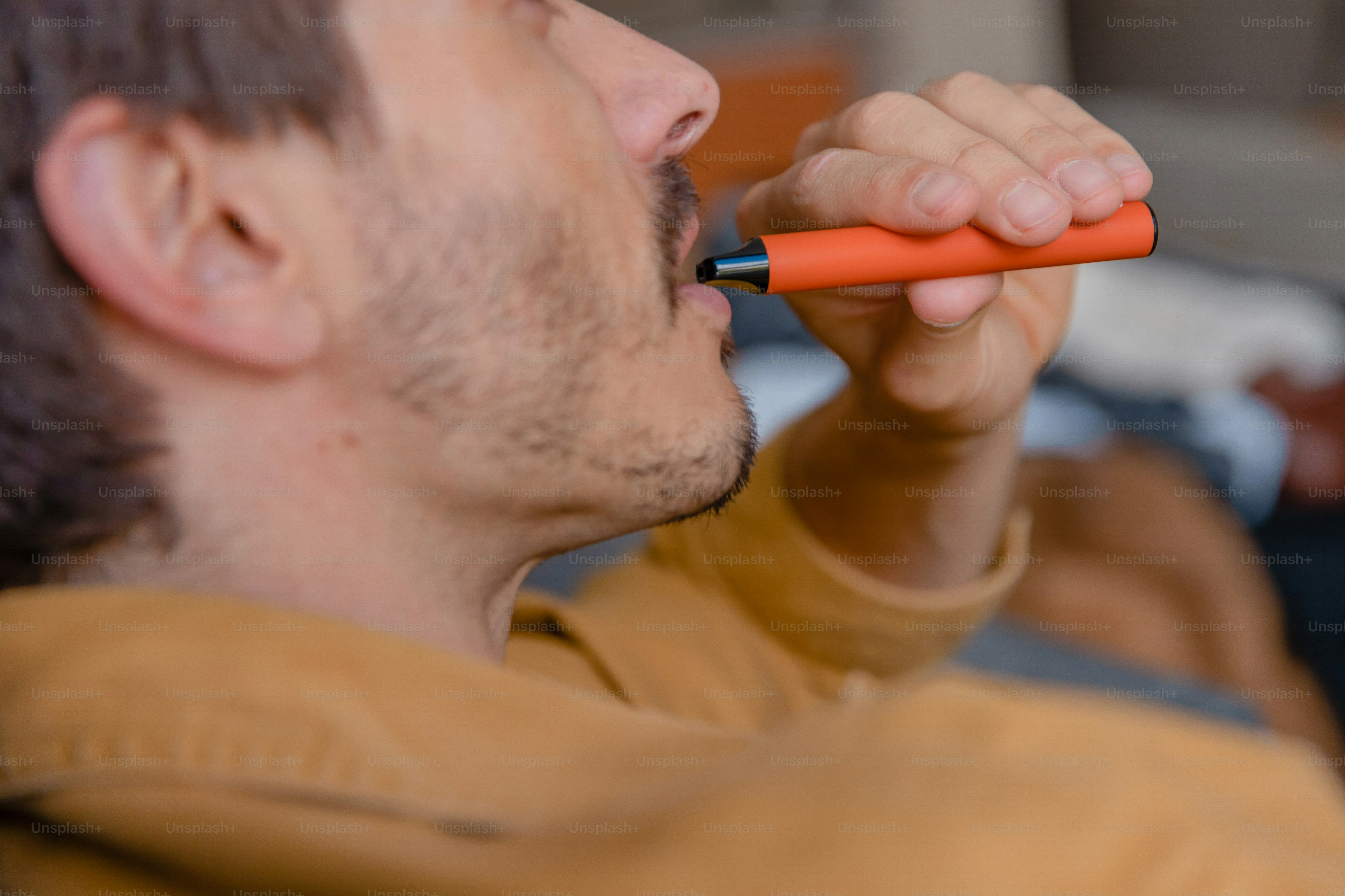 A man holding an orange object in his mouth