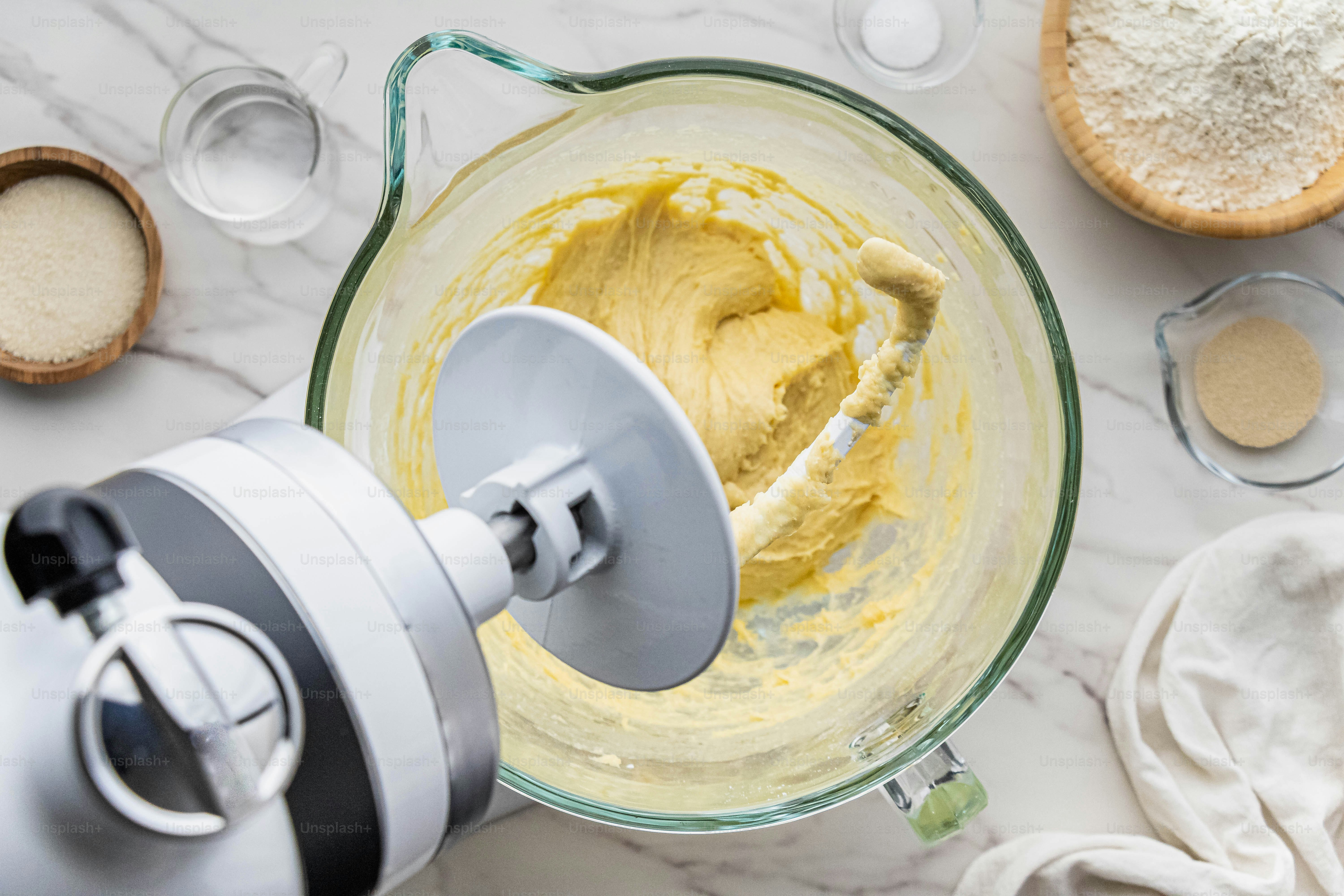 A blender filled with yellow liquid next to other ingredients