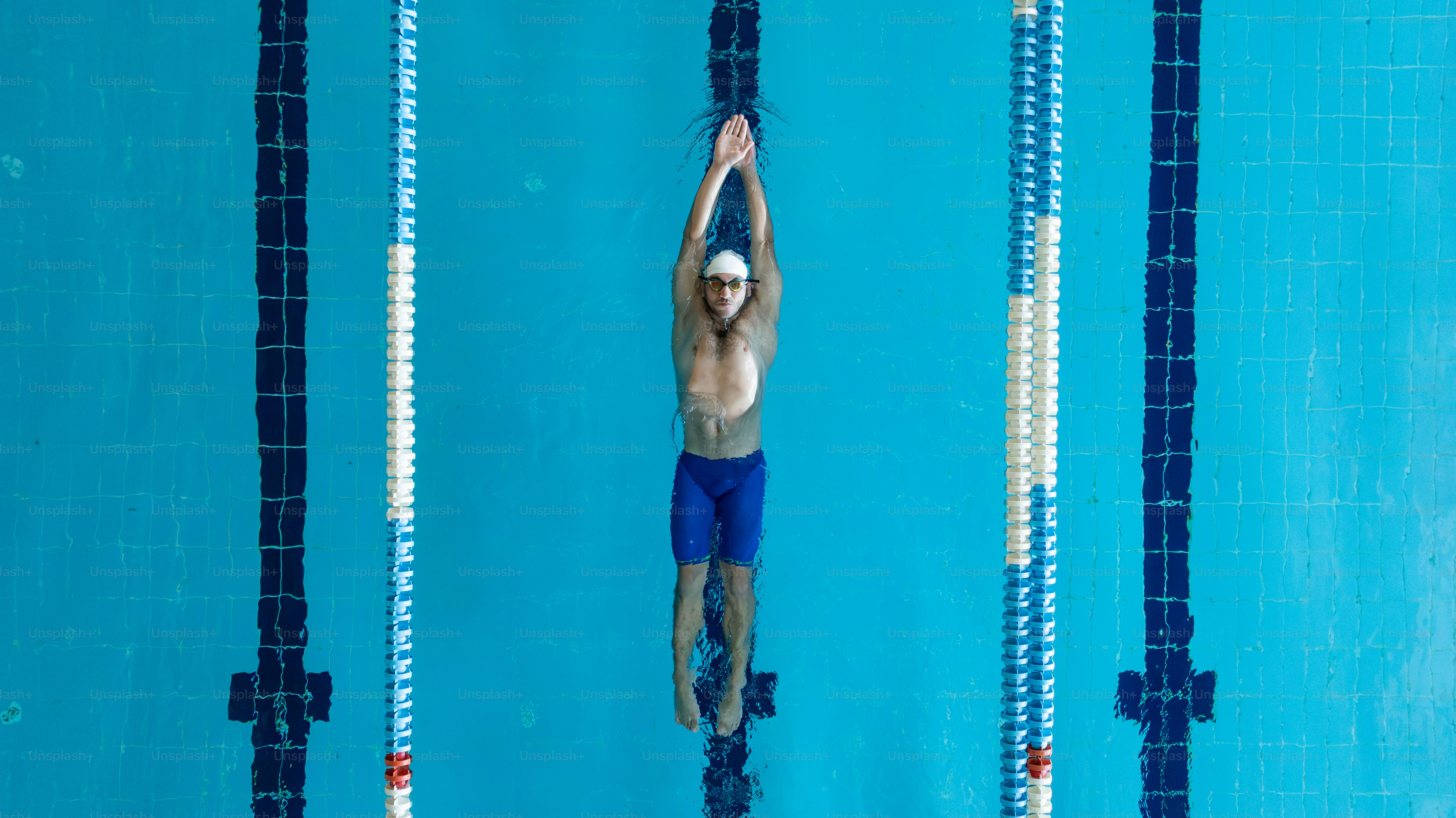 A man is swimming in a pool with his hands in the air photo – Sports ...