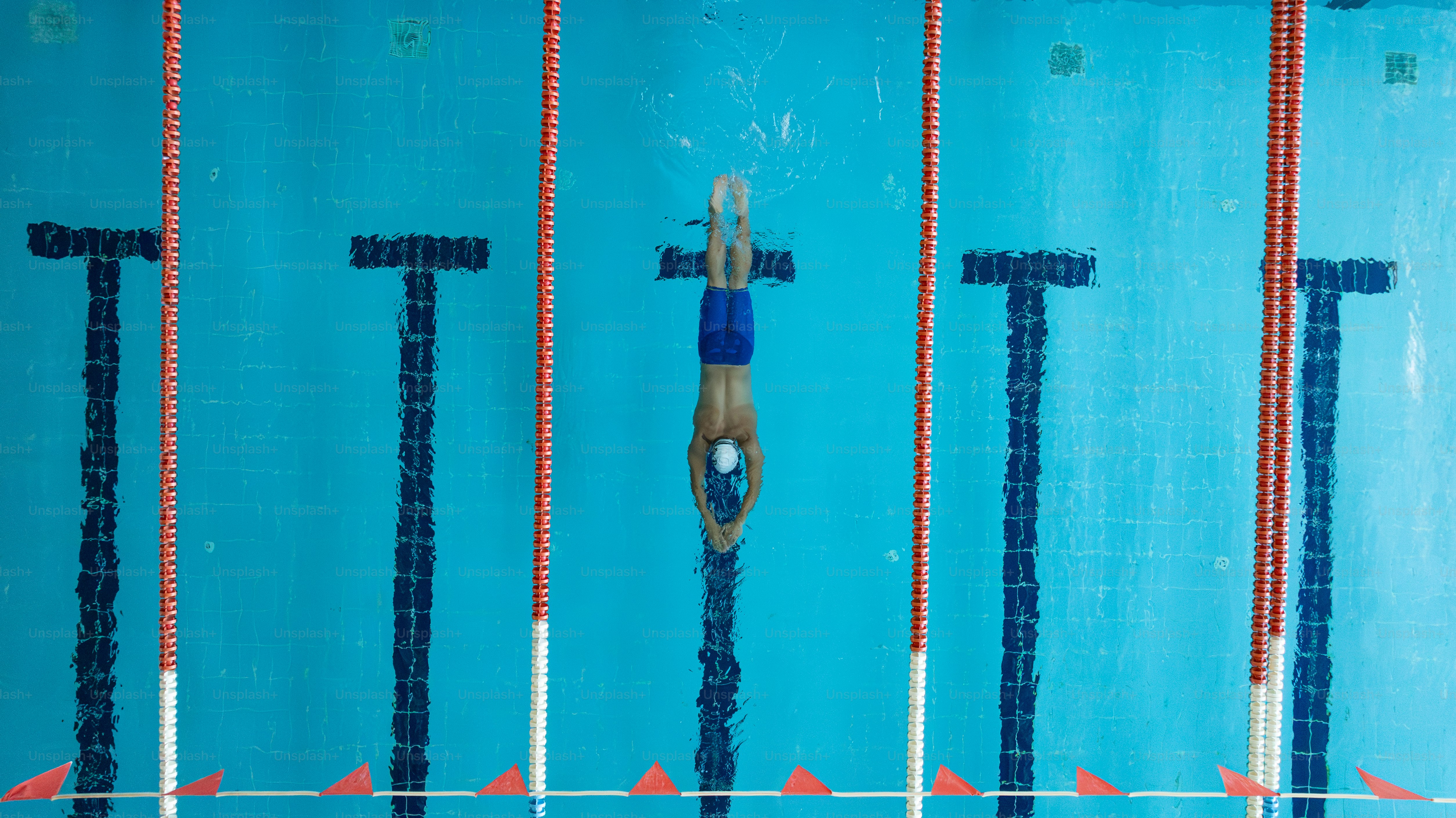 A man swimming in a pool surrounded by poles