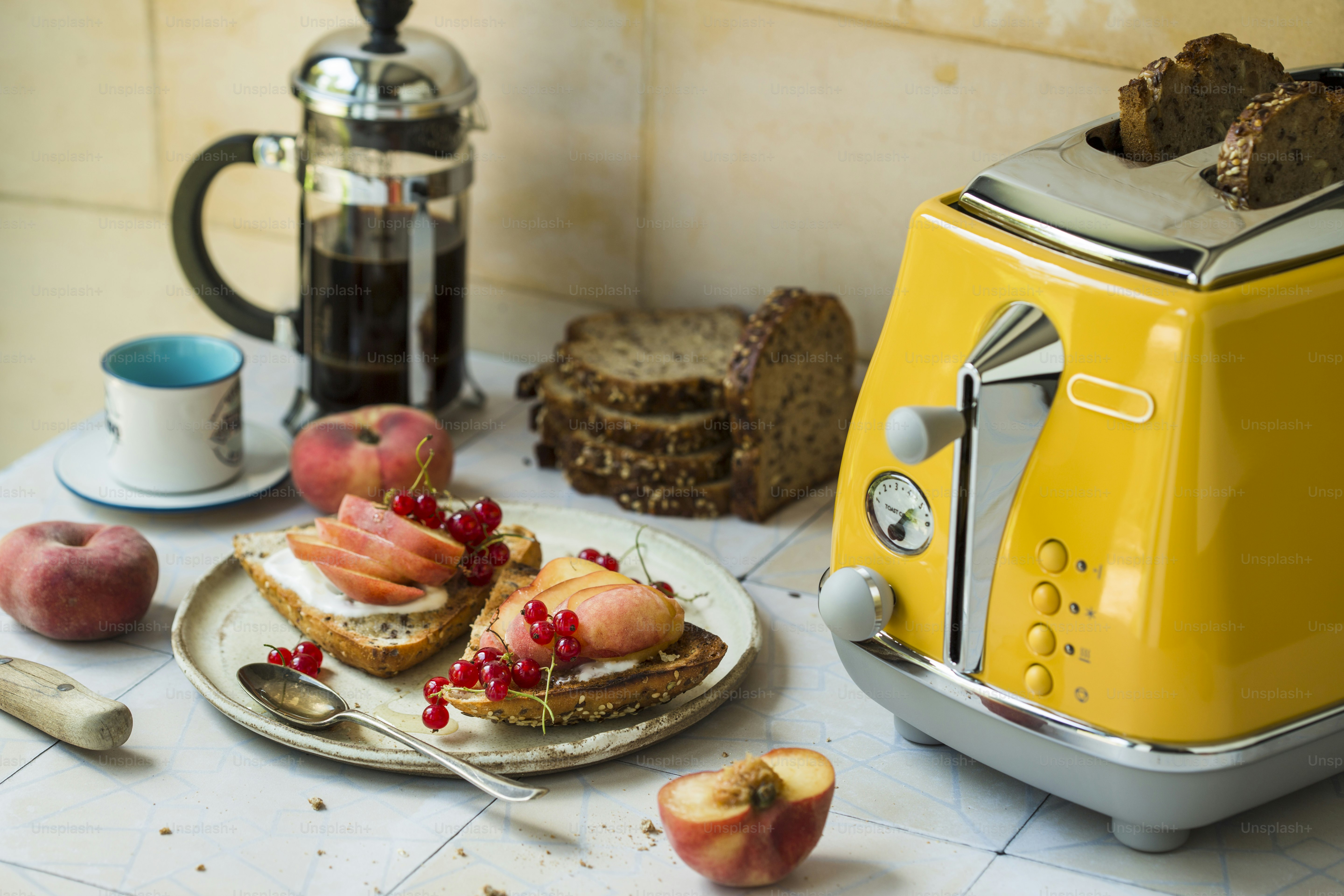A yellow toaster sitting on top of a counter next to a plate of food