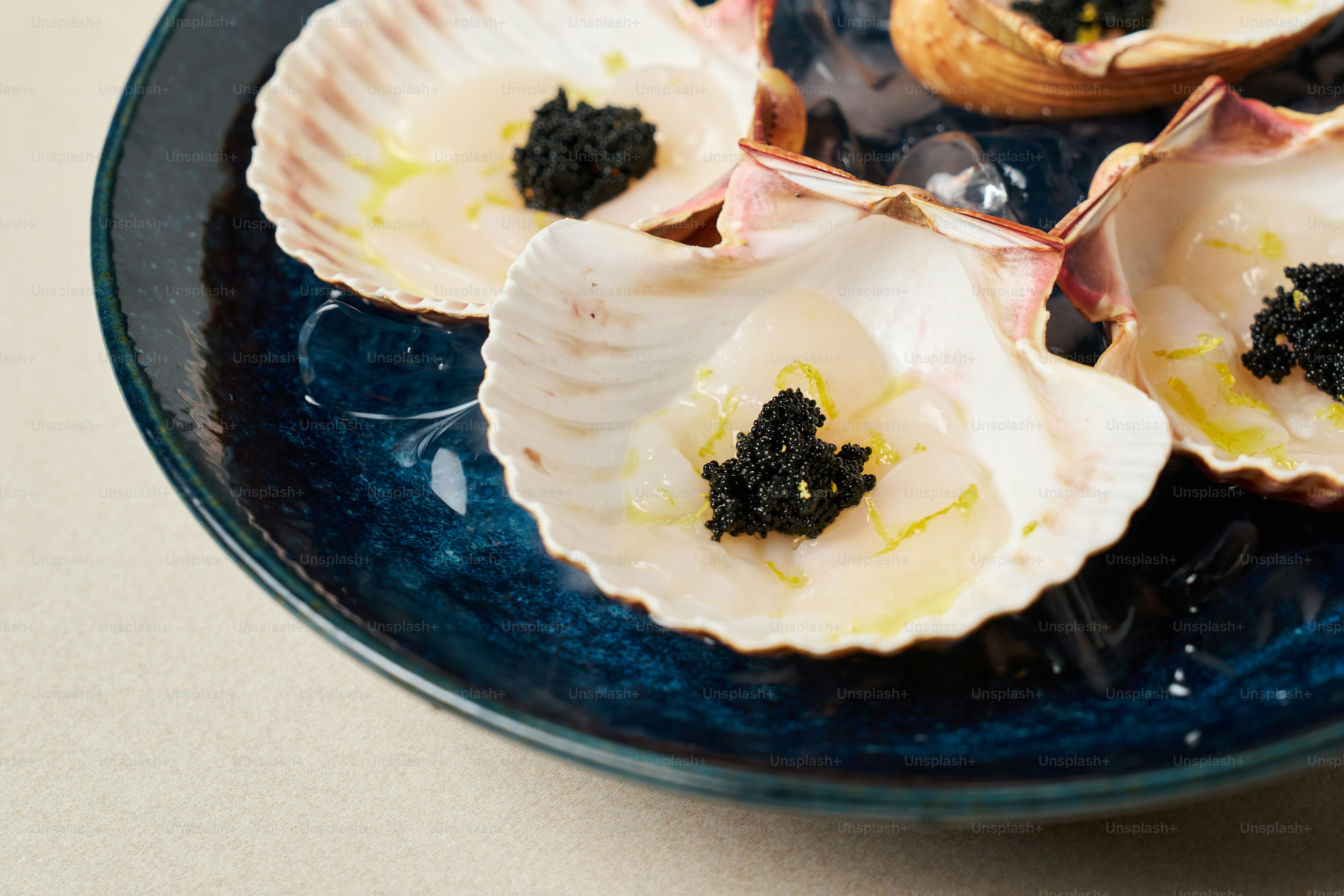 A blue bowl filled with sea shells on top of a table