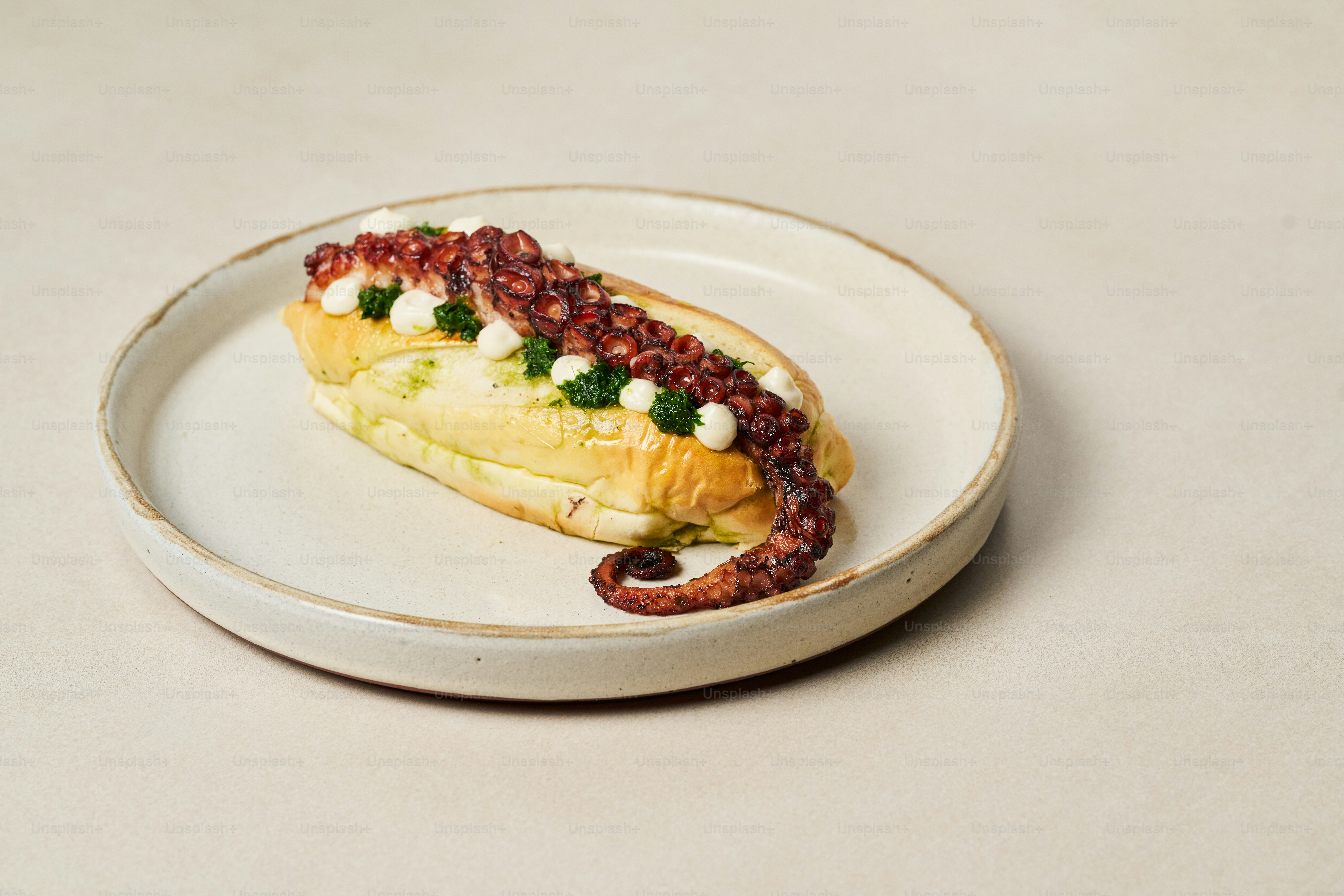 Piring putih di atasnya dengan hot dog yang dilapisi topping