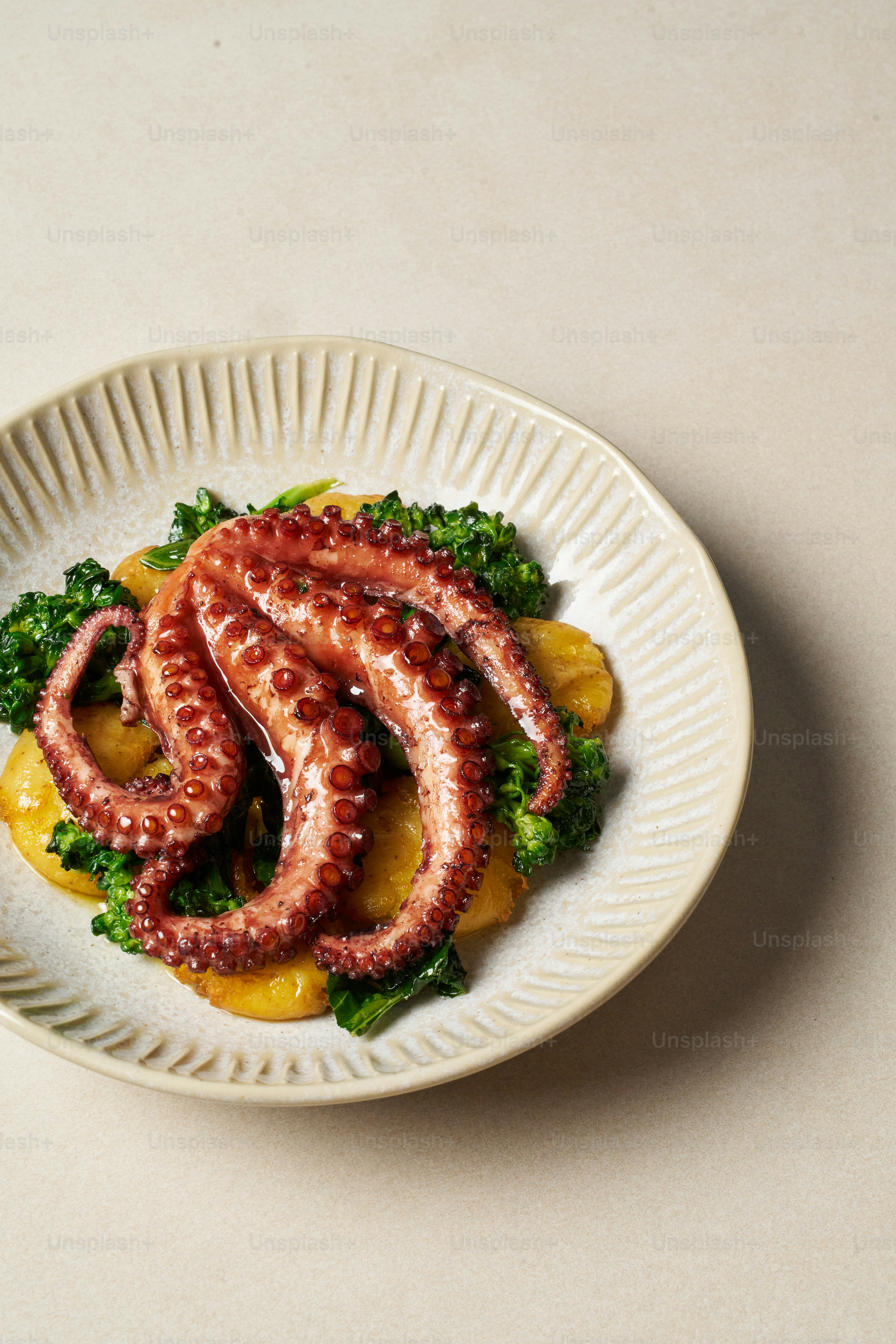 A white plate topped with an octopus and broccoli