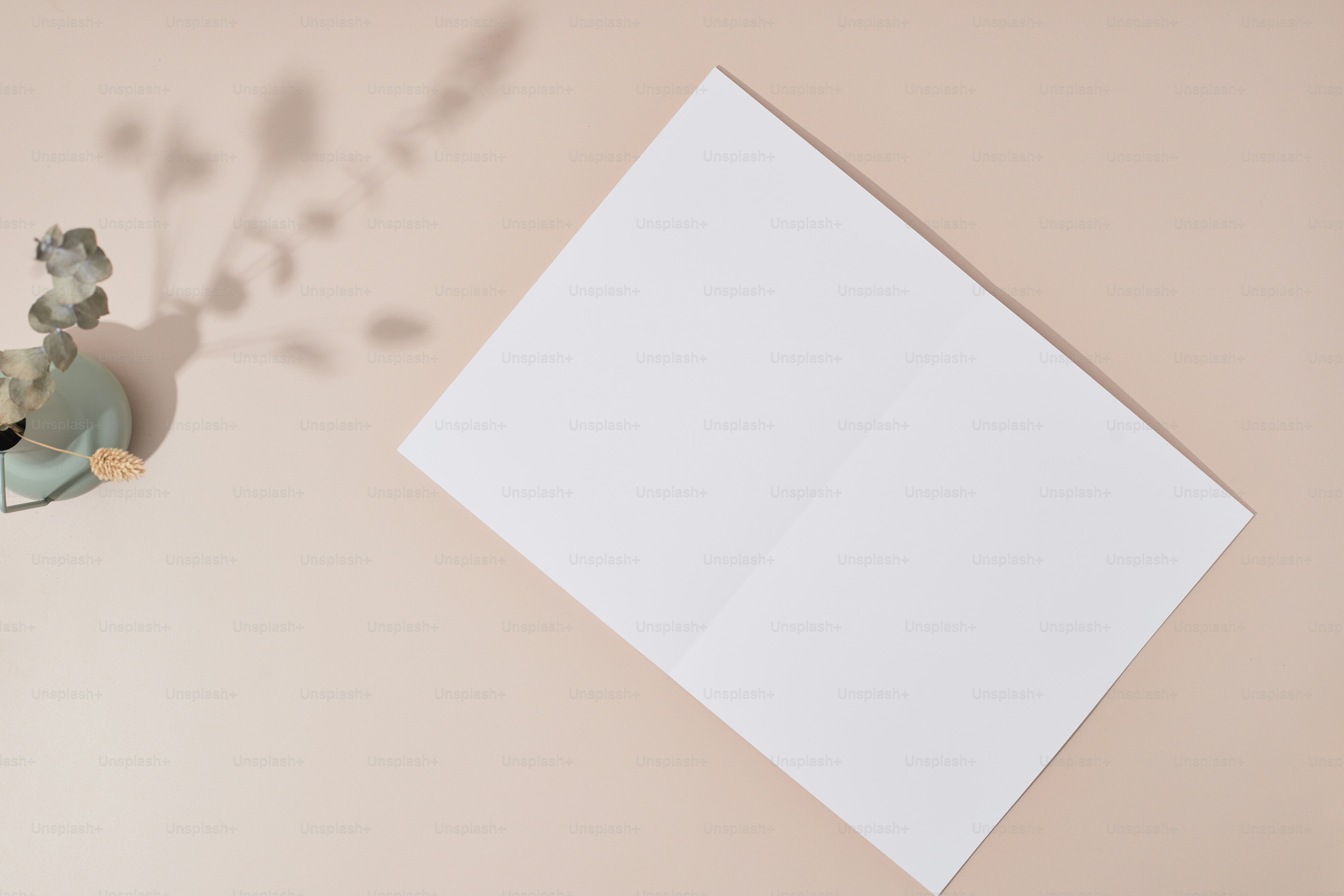 A table with a vase of flowers and a blank paper
