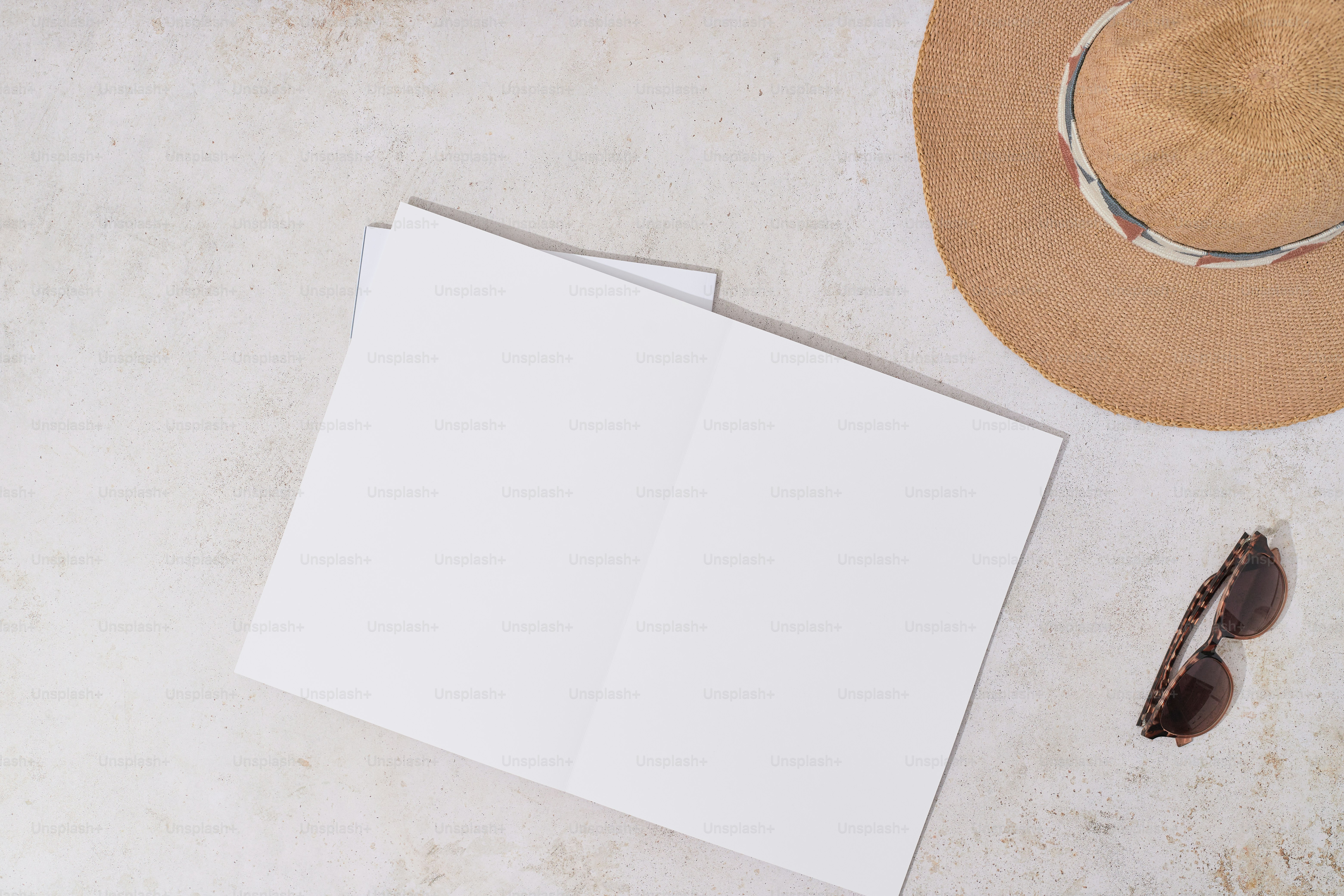 A hat, a pair of sunglasses, and an open book on a table