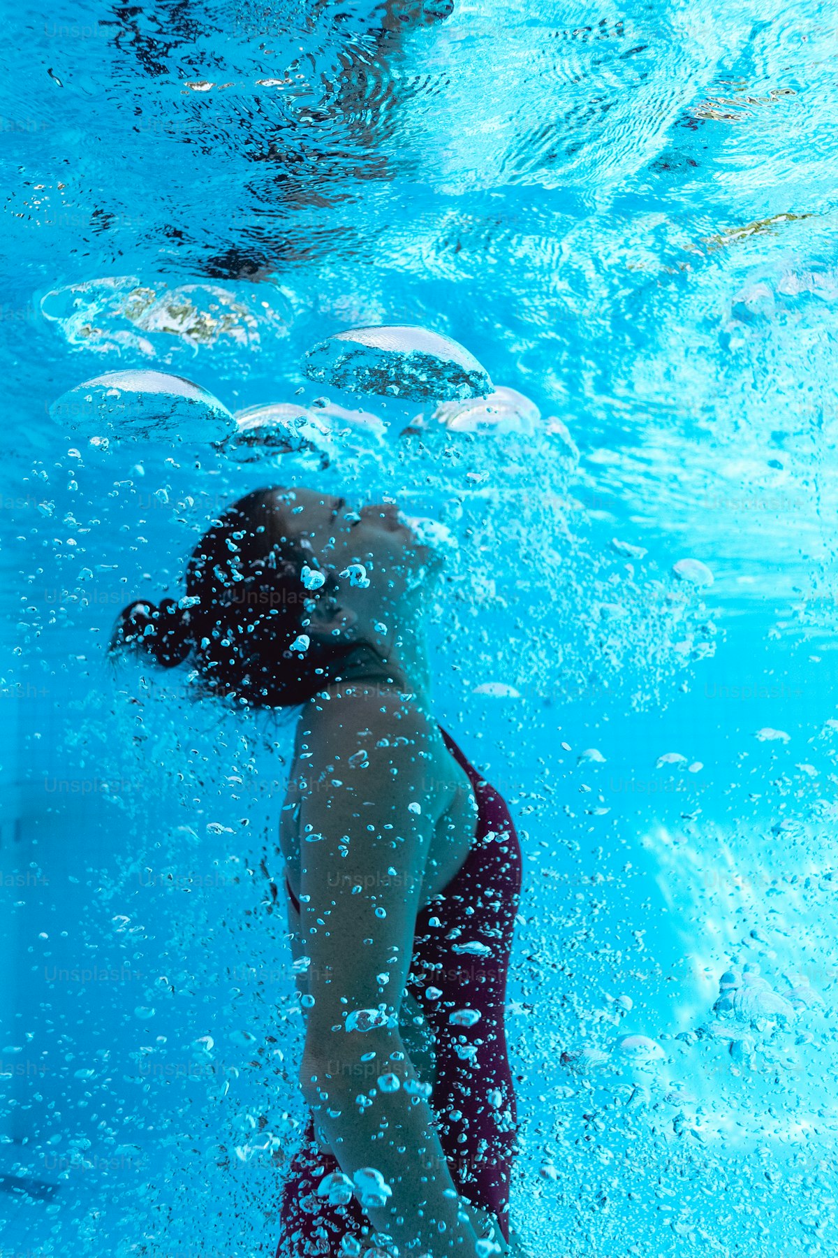 Underwater shot of a person mid-dive in a swimming pool, bodily transition register
